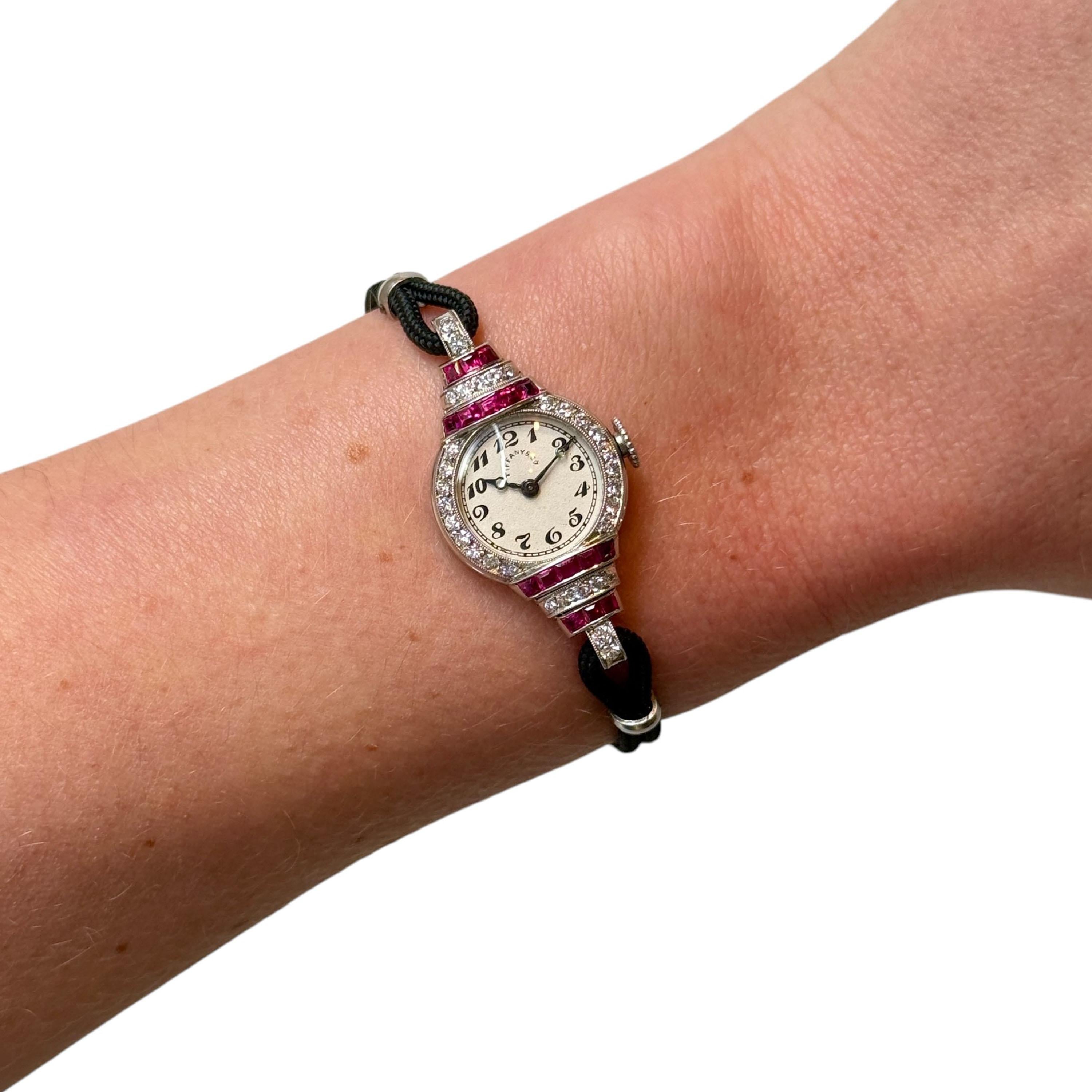 A Tiffany & Co., Art Deco, ruby diamond and platinum cocktail wristwatch, with a circular, white dial, with black Arabic numerals, signed Tiffany & Co., with blue steel hands, with a winding crown, with a curved crystal, surrounded by Swiss-cut