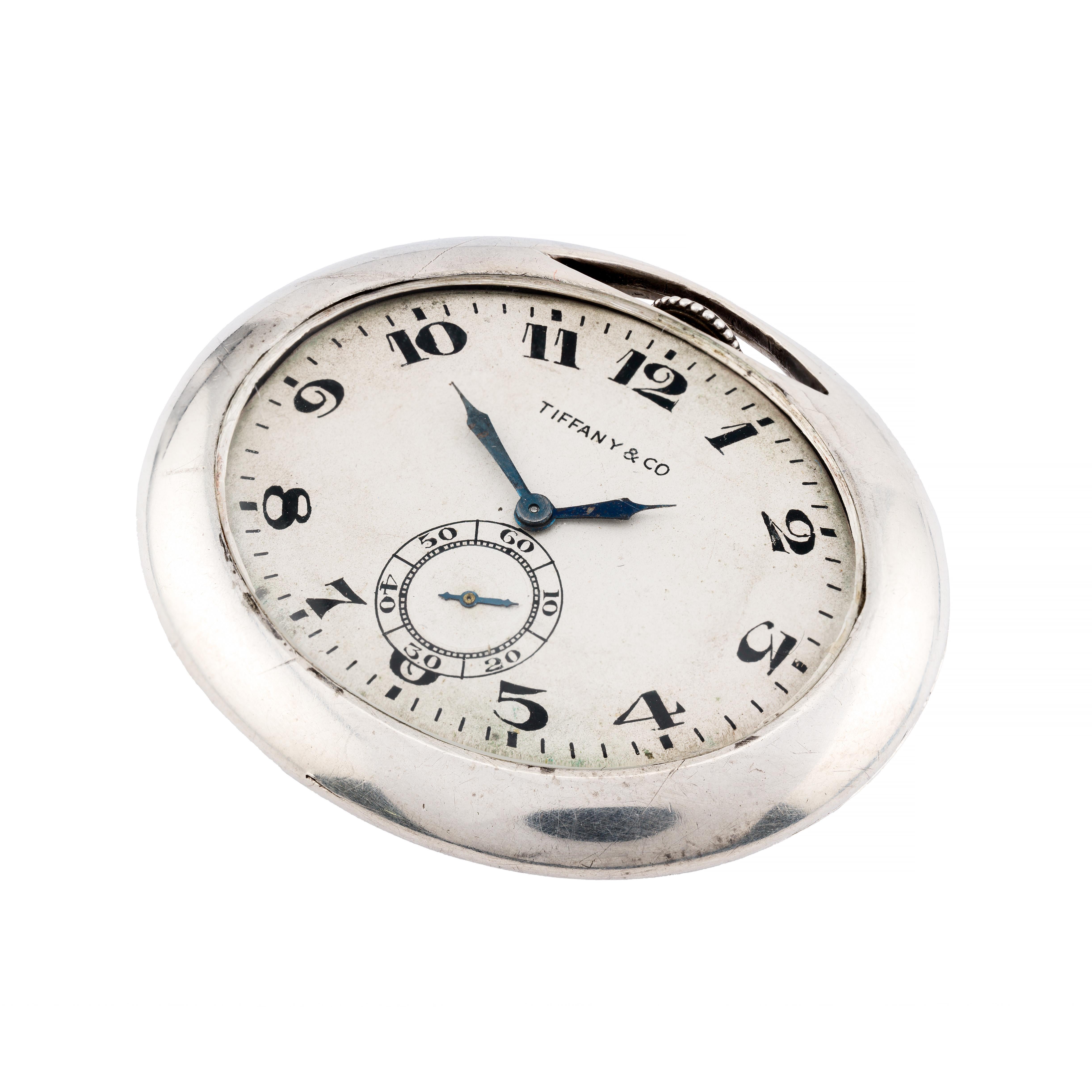 Aston Estate Jewelry présente

Montre de poche art déco Tiffany & Co. en argent sterling.

La montre ovale présente un cadran argenté avec des chiffres arabes audacieux et la signature Tiffany & Co., soulignant son savoir-faire suisse. Le cadran est