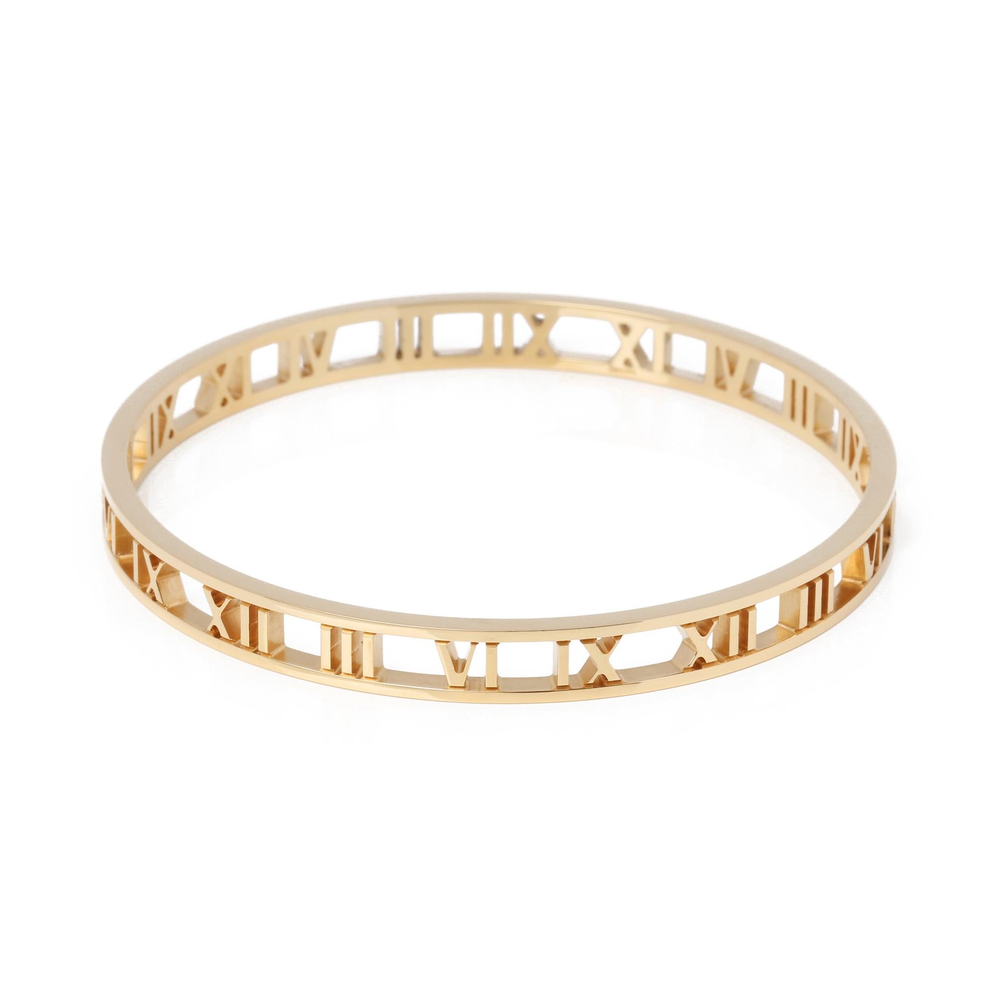 This pull on bangle by Tiffany & Co is from their Atlas Collection and features an open roman numeral design in 18ct yellow gold. The bangle is the larger option with a circumference of 19cm and an internal diameter of 6.5cm. Complete with Tiffany &