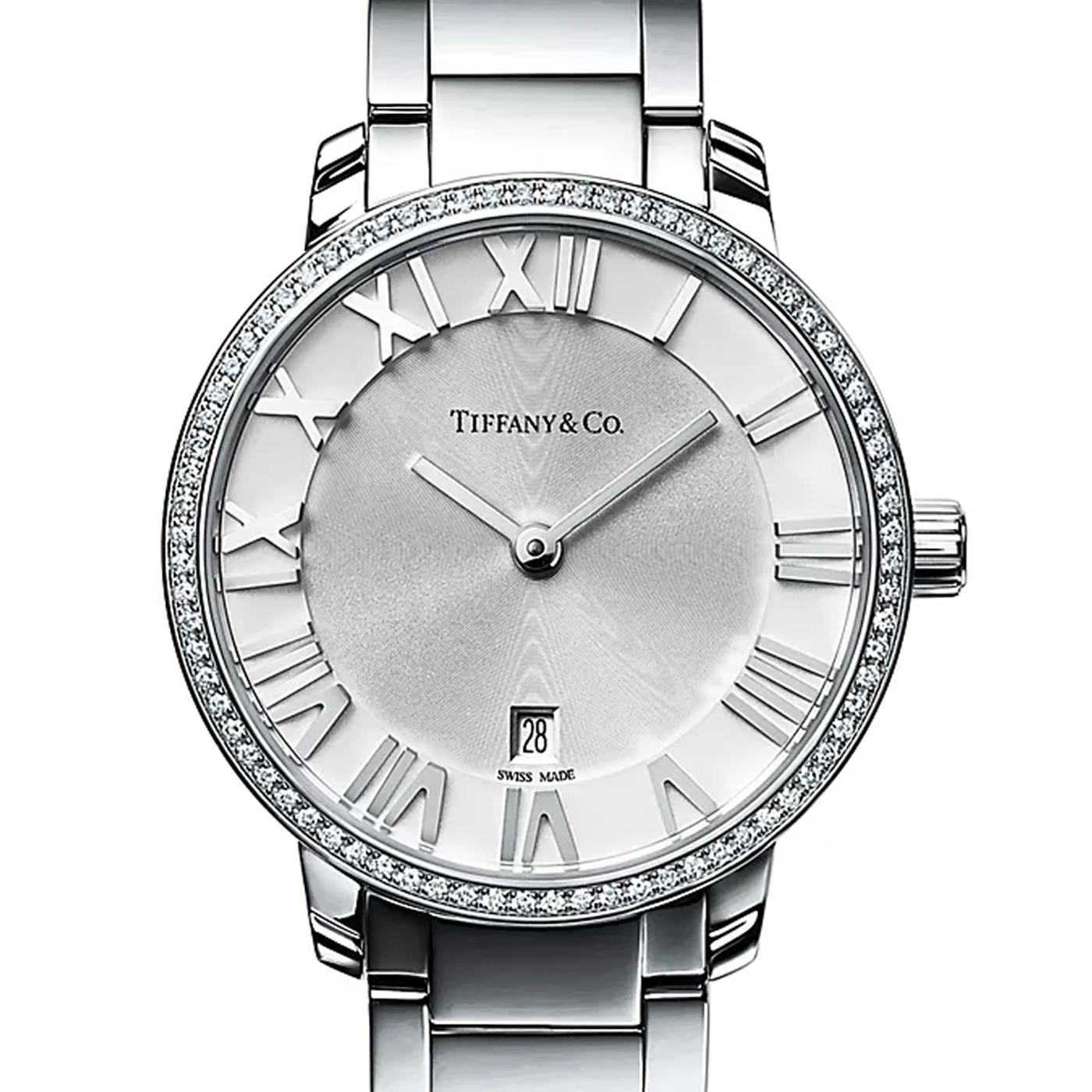 Se trata de un reloj de mujer de acero inoxidable. Tiene una esfera plateada azulada, una caja de 31 mm engastada con diamantes brillantes redondos, movimiento de cuarzo y es de fabricación suiza. Es resistente al agua hasta 50 metros/160 pies/5