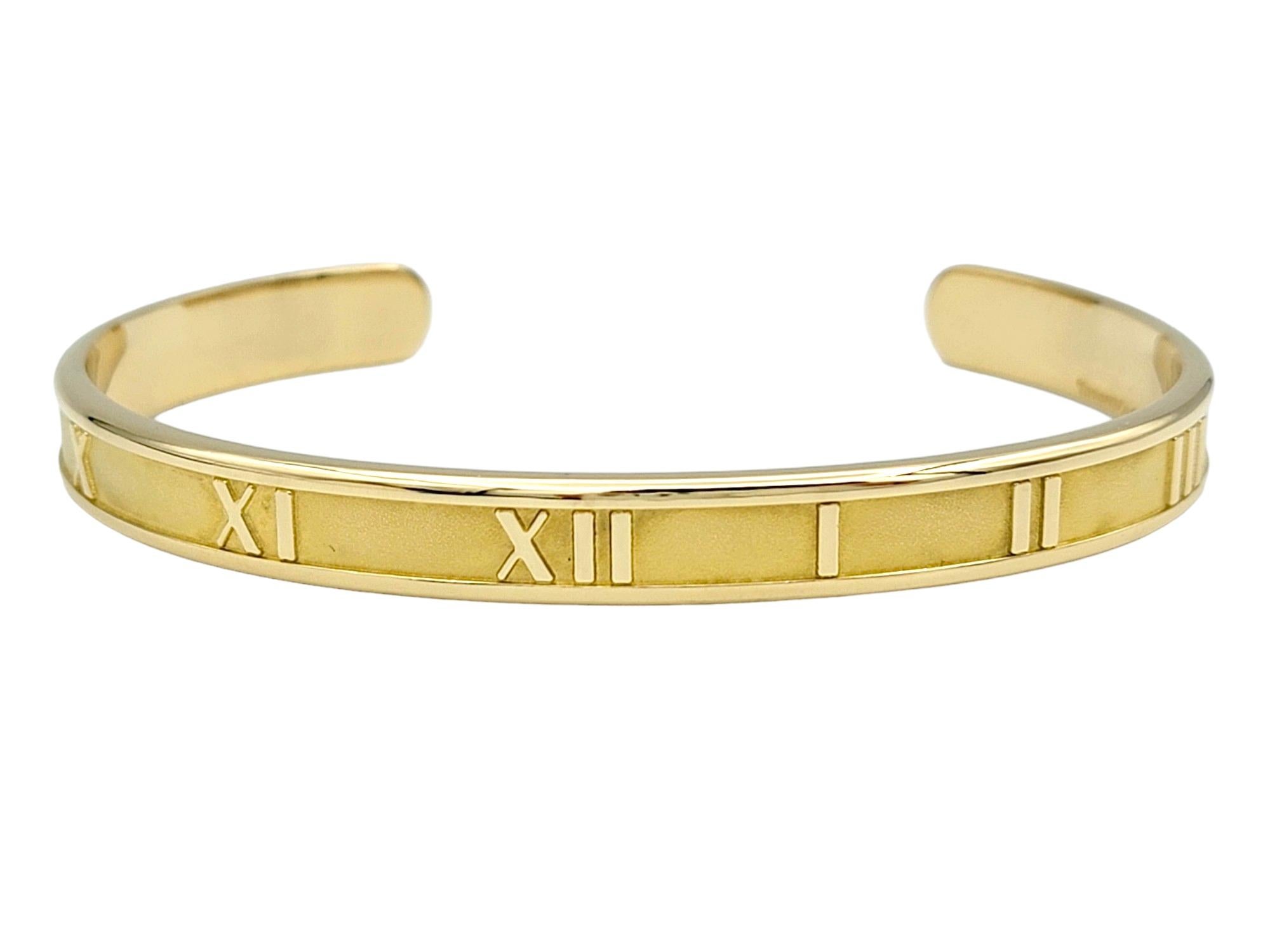 This gorgeous Tiffany & Co. Atlas cuff bracelet in 18 karat yellow gold is a timeless and elegant piece of jewelry that exudes sophistication and luxury. The sleek and minimalist design of the cuff bracelet showcases the bold Roman numeral motif,