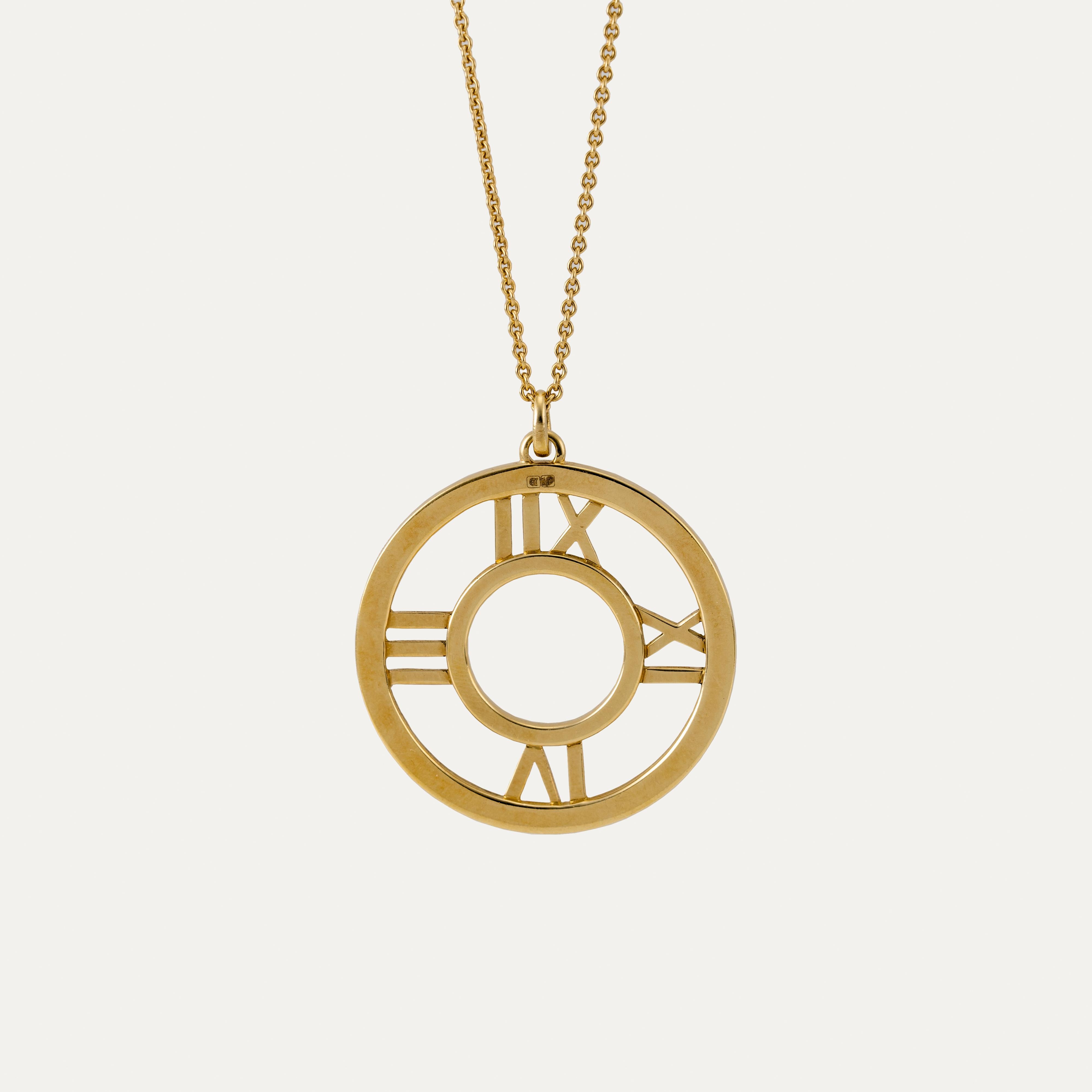 Ce collier Atlas emblématique en or jaune de Tiffany & Co. capture l'esprit durable de la collection la plus reconnaissable de la maison. Réalisé en or jaune 18 carats, le collier présente un pendentif circulaire avec des chiffres romains découpés,