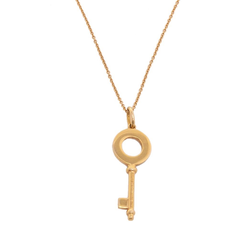 An elegant design from Tiffany & Co., this necklace features a delicate gold chain that is secured by a spring-ring clasp. An ornate key dangles as a pendant. It has Roman numeral hour markers embedded in the design. Tiffany keys are designed to