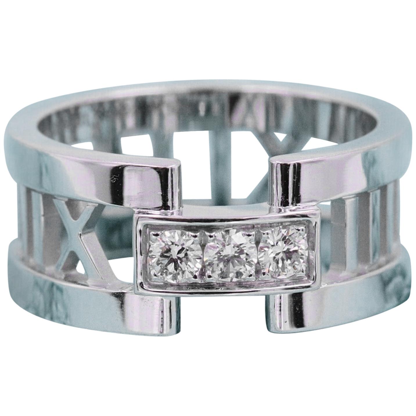 Tiffany & Co.
Style:  Atlas Open Band Ring with Diamonds
Metal:  18K White Gold
Width:  8 MM
Size:  5.25 
Diamonds:  3 Round Brilliant Diamonds weighing 0.19 tcw G color, SI clarity
Hallmark:  ATLAS ©2003 TIFFANY&CO. 750 ITALY
Includes:  T&C Jewelry