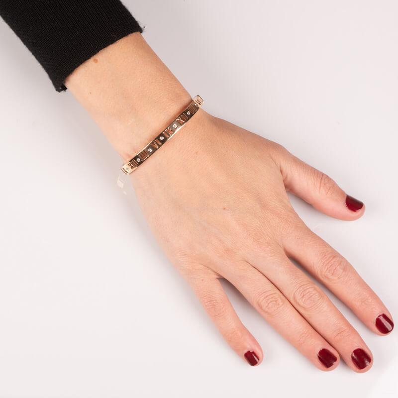 Crafted from 18 karat rose gold, this bracelet features the signature Roman numeral motif with 0.14ctw bezel set diamonds and a hinged band. This is a classic Tiffany style. This will fit up to a 7