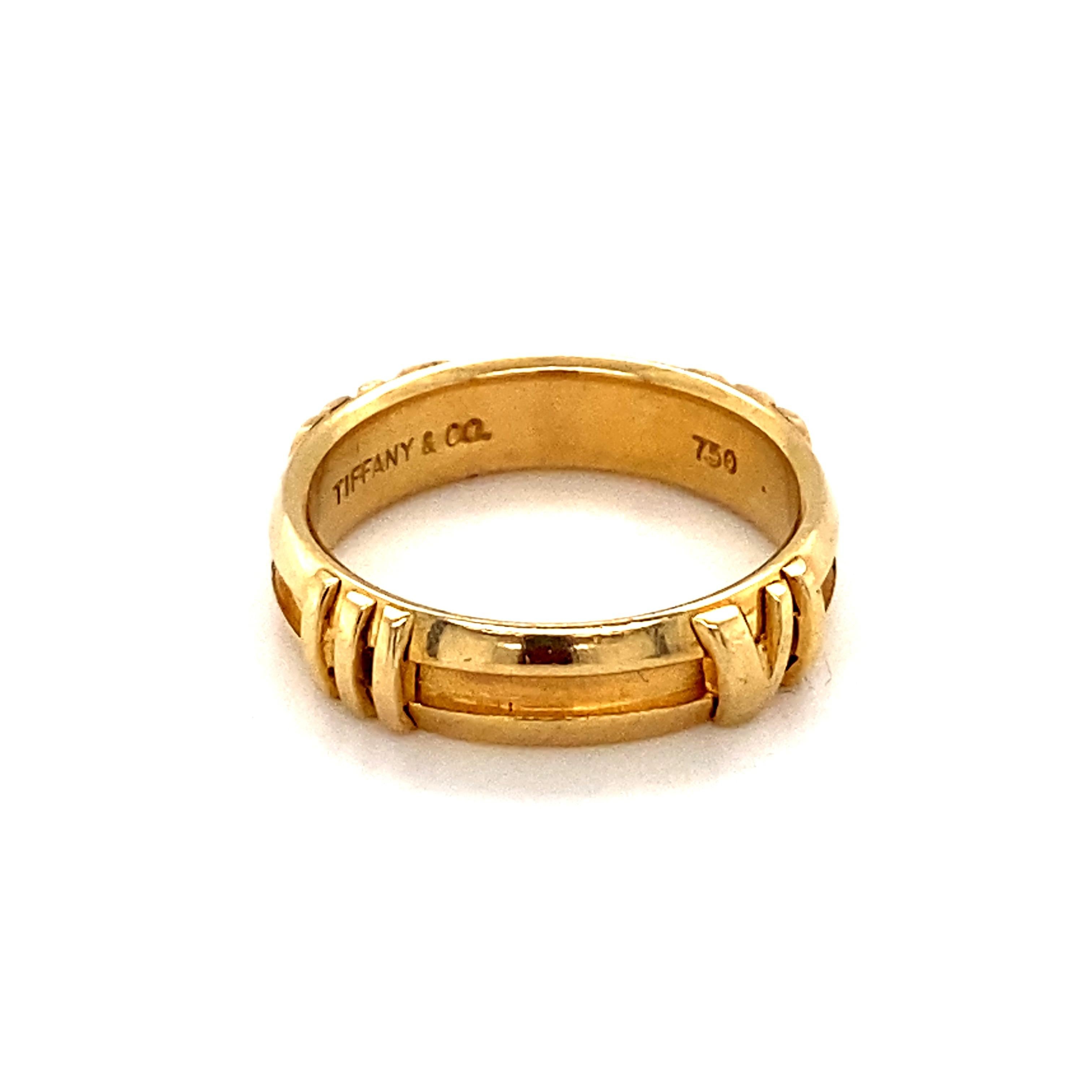 This beautiful gold band by famed jewelry company Tiffany & Co is part of the Atlas collection. Designed with Roman numerals and brushed gold, this band is a stunning piece that can be worn by all genders. It is stamped with 750 and the maker's