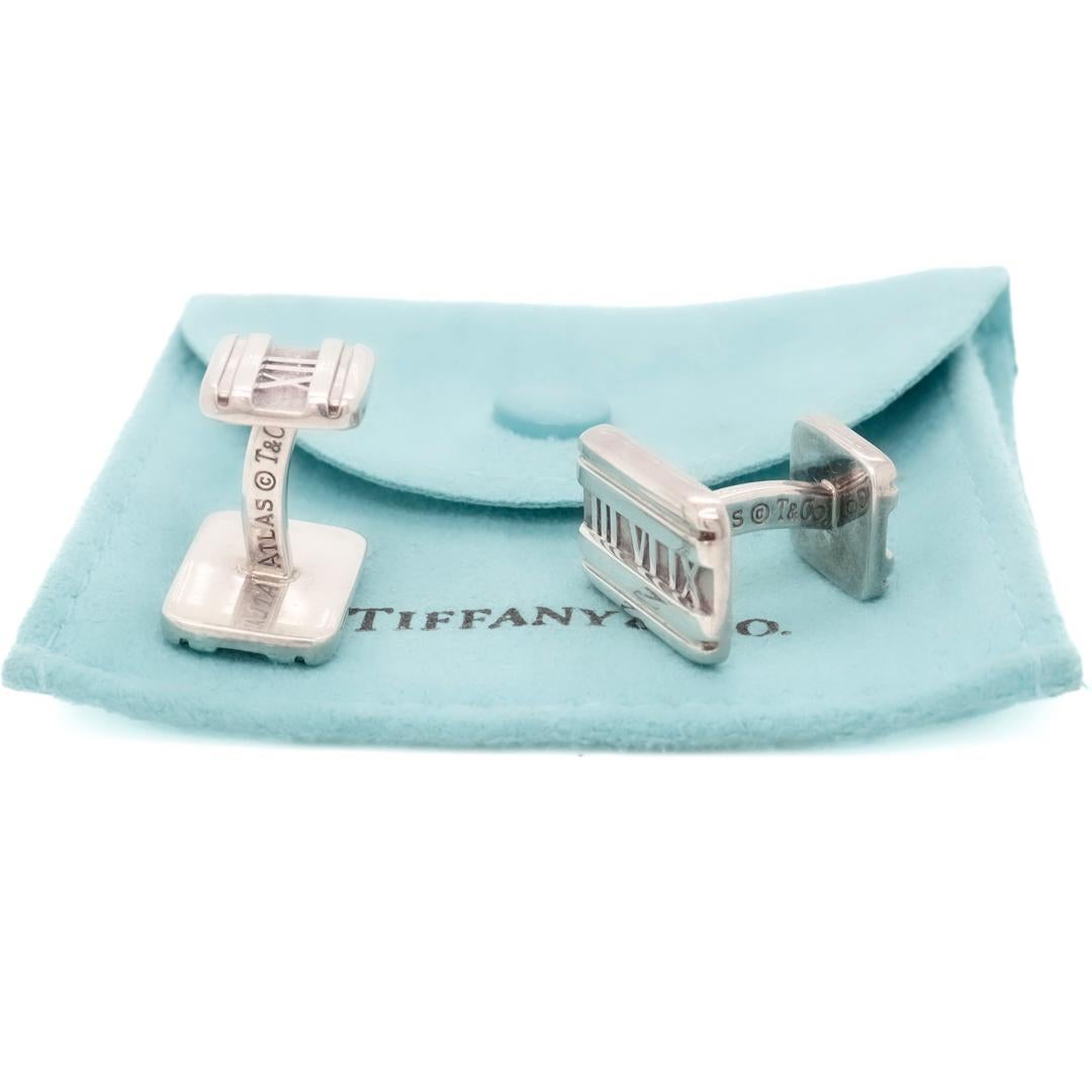 A fine pair of Atlas cufflinks.  

By Tiffany & Co.

In sterling silver.

Together with their original Tiffany pouch.

With raised Roman numerals to the centers of the faces and fixed backs.  

The 'Atlas' collection was designed by John Loring in