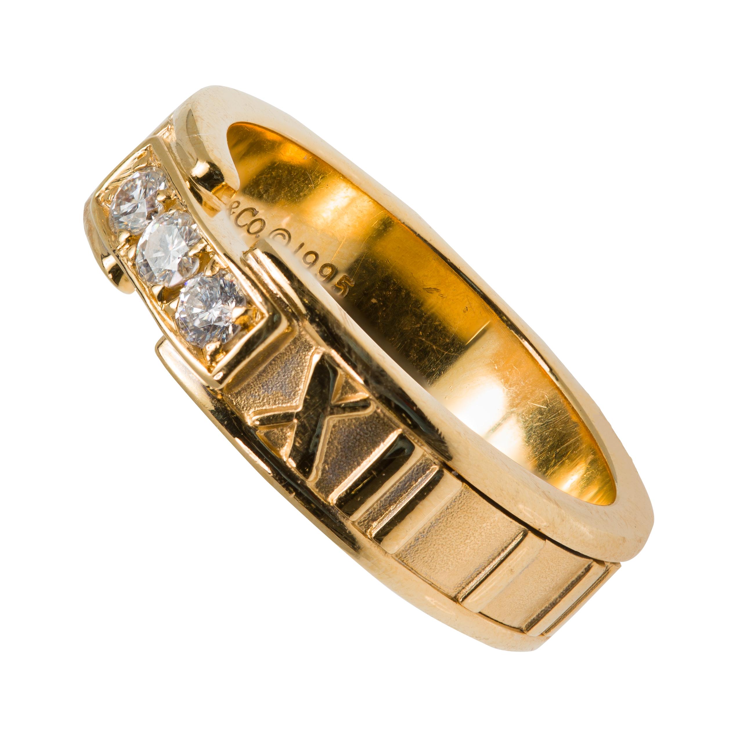A signed Tiffany & Co. Atlas Roman Numeral design wedding ring circa 1995, with three Diamonds in 18K yellow gold, size 6.5. Created in the later years of the 20th century, this iconic Atlas Roman Numeral ring features three frontal full round-cut