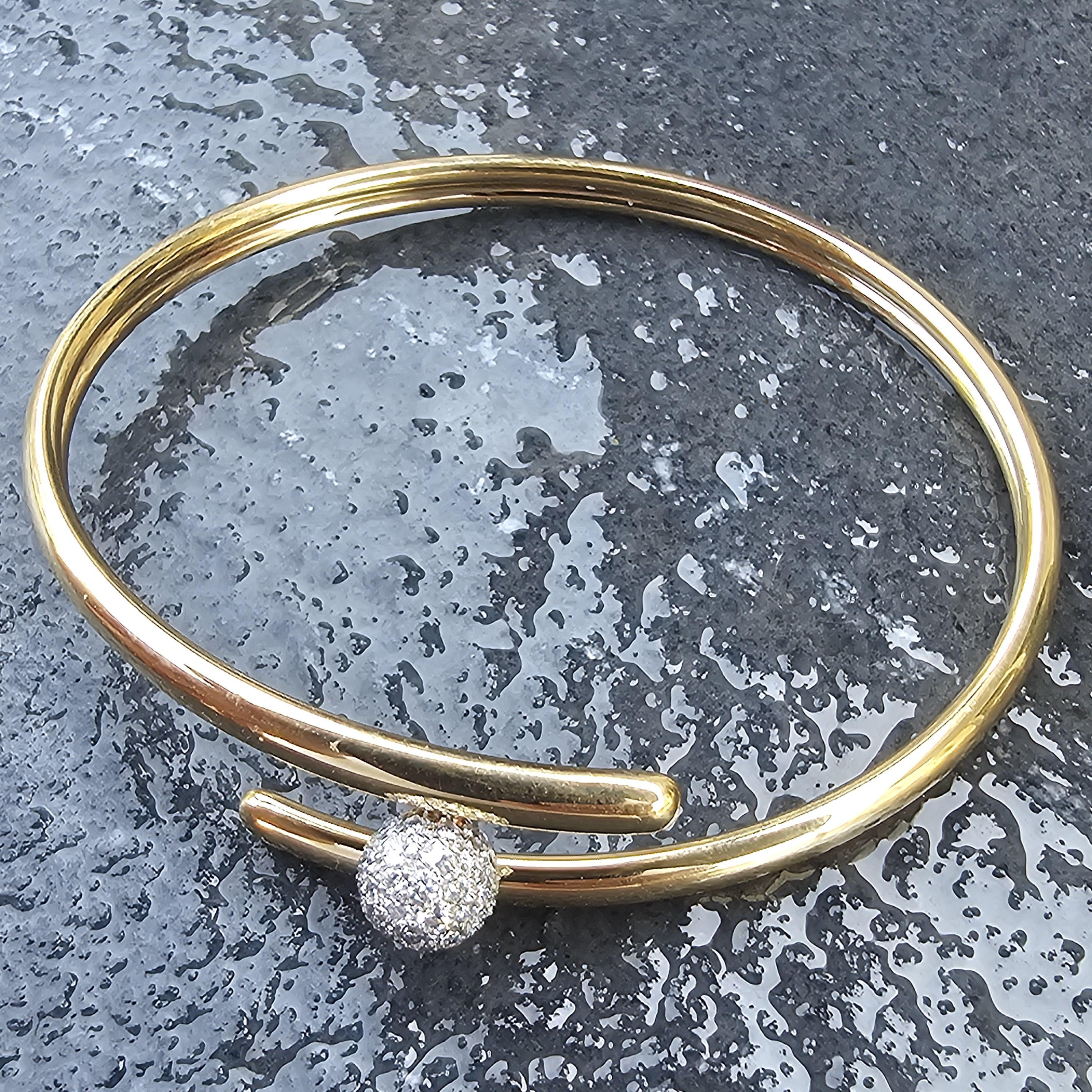 Élevez votre collection avec ce bracelet bangle de Tiffany & Co. Réalisée en or jaune 18 carats, elle présente une remarquable boule en platine ornée de diamants blancs. Le design est élégant et moderne, parfait pour toutes les occasions. Avec un