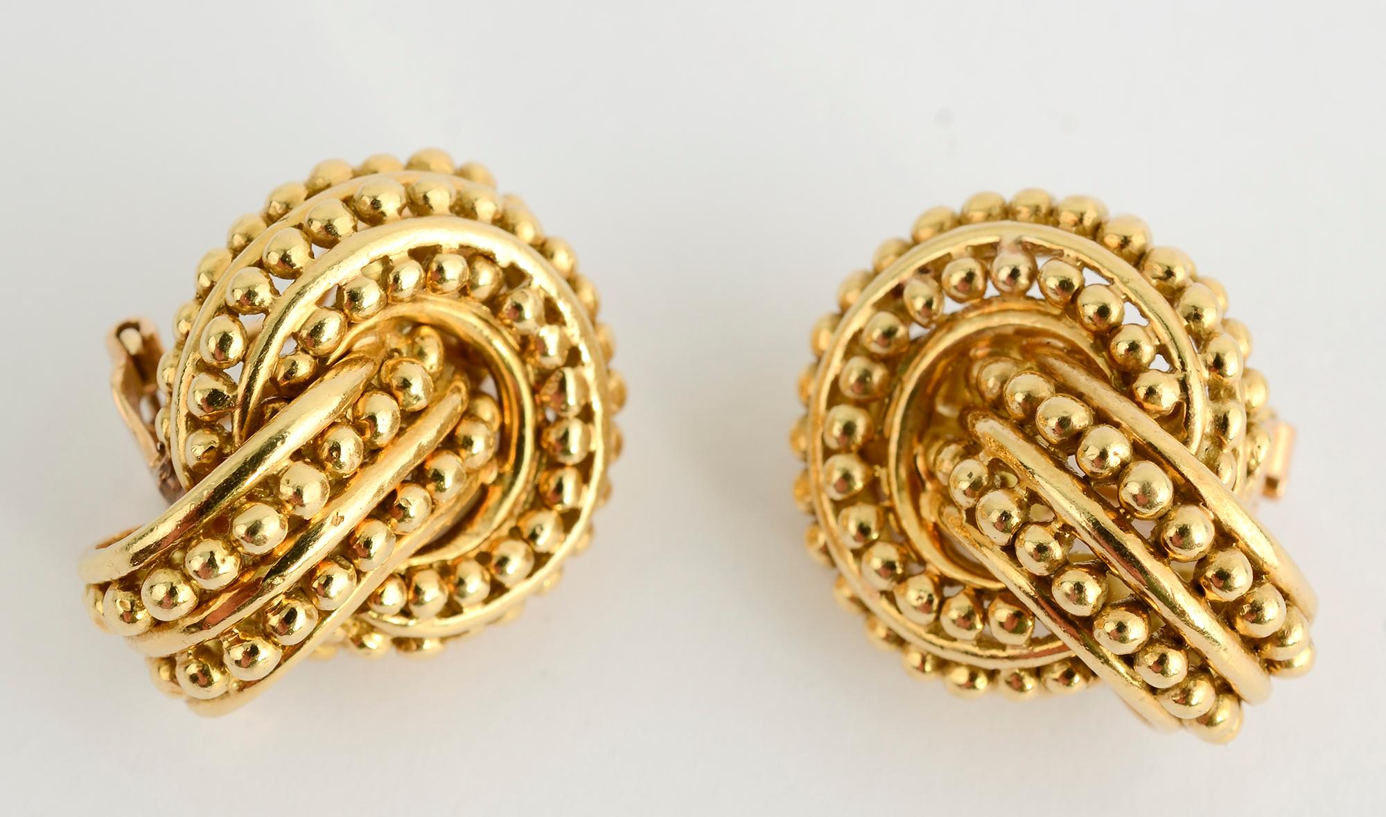 Wonderfully textured and sculptural earrings by Tiffany. An oval half hoop, set on a slight angle, intertwines with a gold circle. Three rows of gold beading are on the circle and two rows on the oval. The earrings measure 1 inch long and 3/4 inch