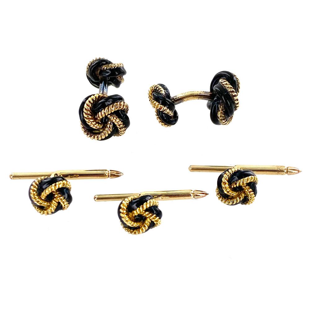 Tiffany & Company black enamel and yellow gold cufflinks and stud set. The cufflinks measure 12 x 22m, and each stud knot measures approximately 9.5mm. The cufflinks are signed Tiffany & Co. 18k. The set comes in it's original Tiffany box. All of
