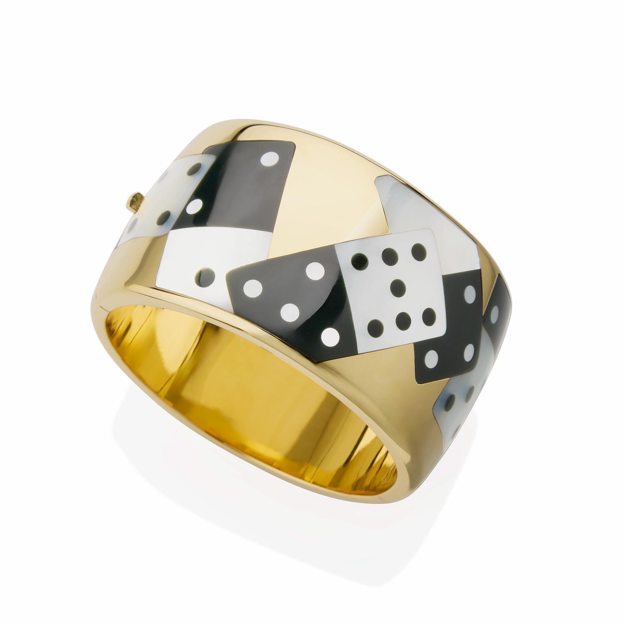 Created in the early 1990s, this Tiffany & Co. bangle bracelet is composed of 18K gold, mother-of-pearl and black jade. The broad hinged 18K gold bangle is inset with overlapping black jade and mother of pearl dominoes. This intriguing and playful