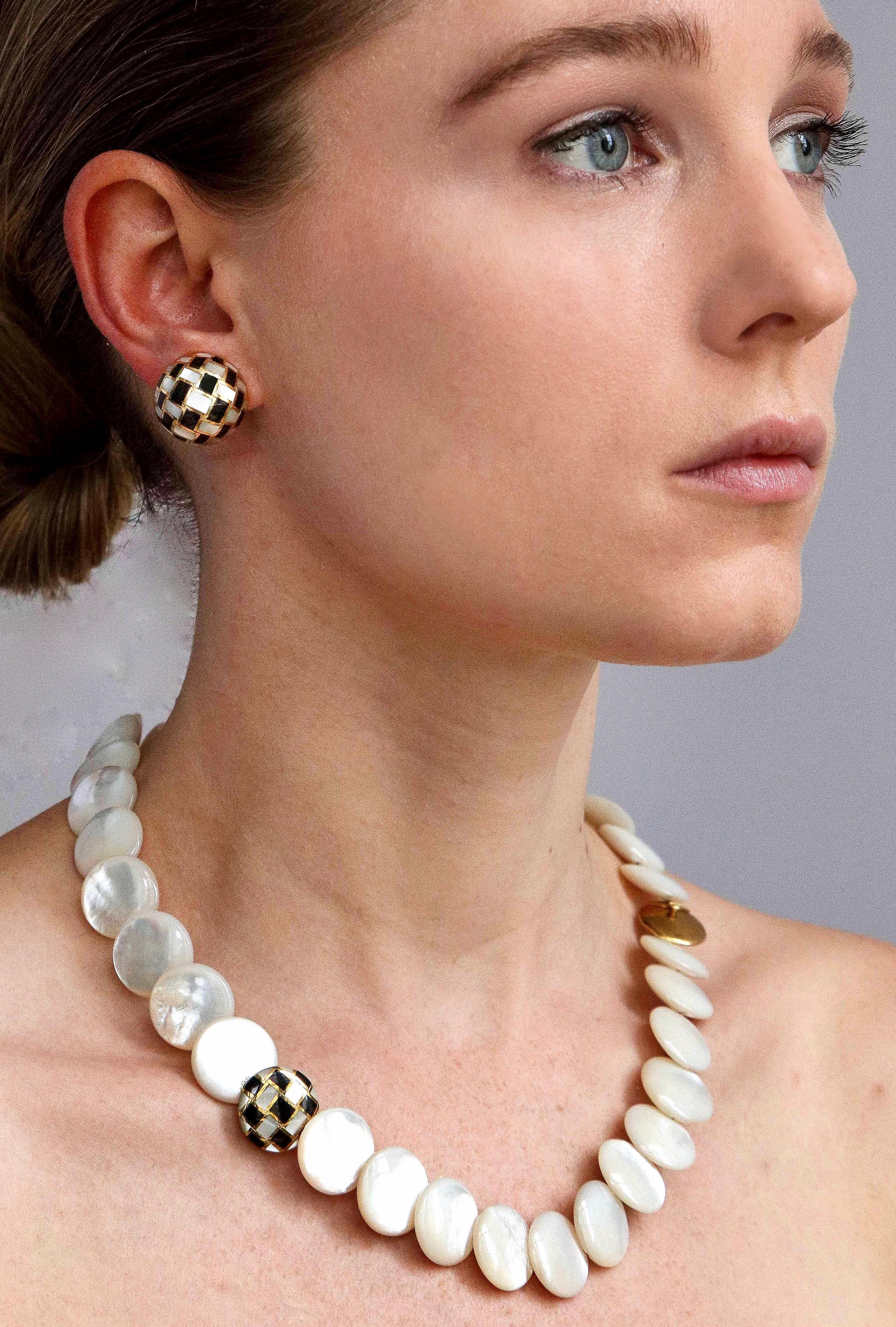 Simply chic for any age, a Tiffany & Co. necklace of carved mother-of-pearl disks with 18K gold clasp and a perfectly placed checkered disk of pearl and black jade inlay with matching ear clips. Necklace measures 3/4 inch x 20 inches long weighing