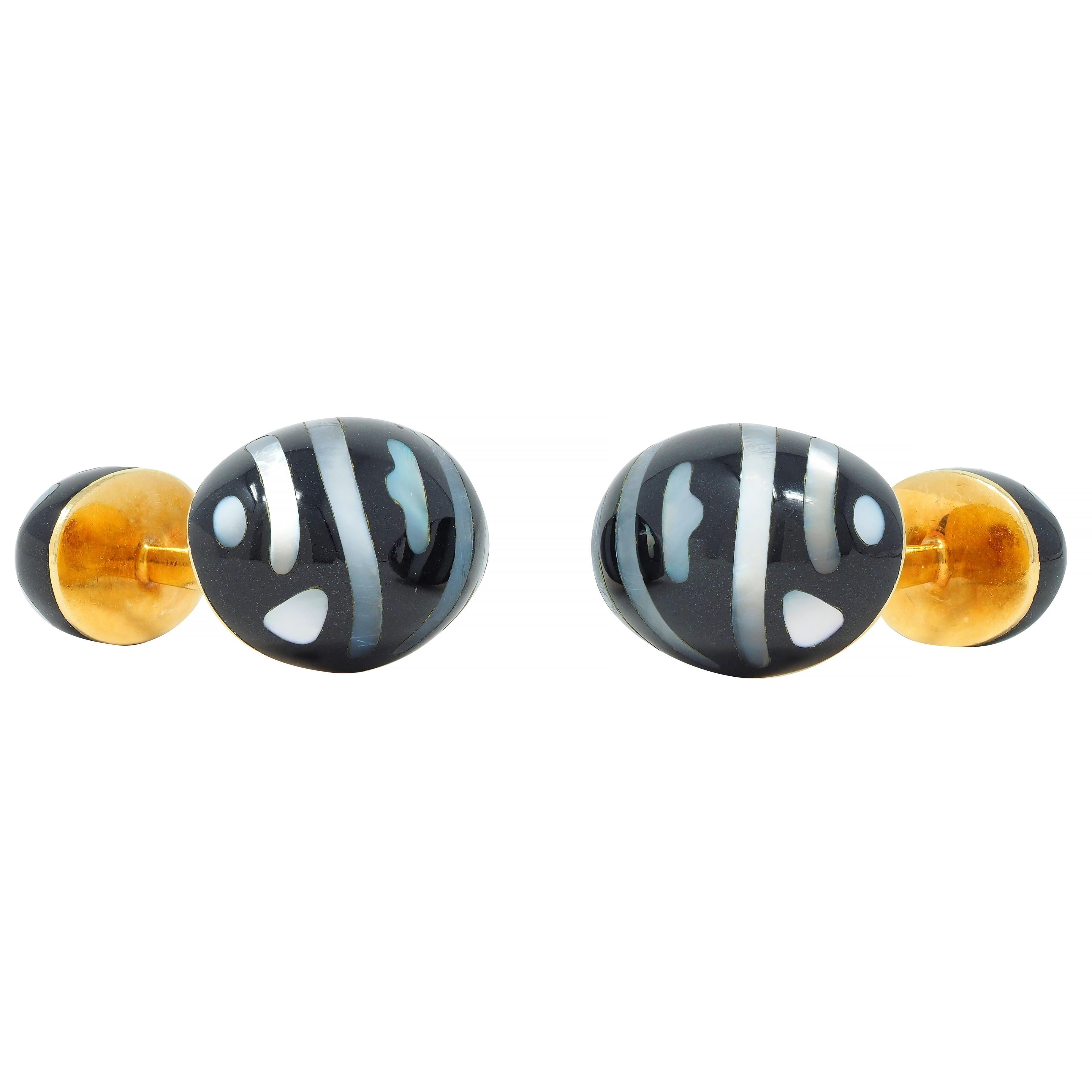 Designed as barbell style cufflinks terminating with one large and one small oval 
Comprised of carved jade cabochons - opaque glossy black 
Inlaid with organic mother-of-pearl stripe pattern
Translucent white with strong iridescence 
Stamped for 18