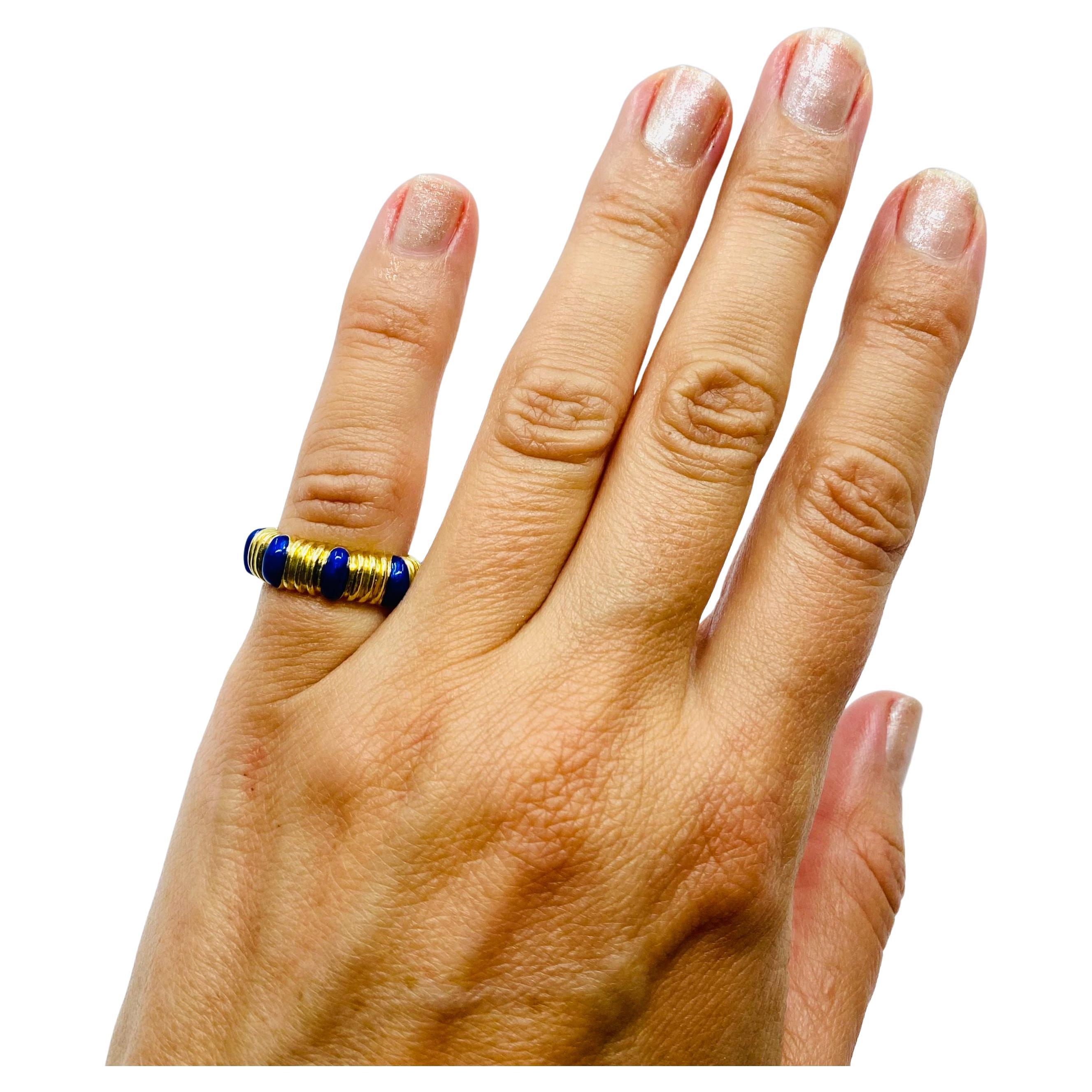 An 18k gold and blue enamel Tiffany & Co. band ring. This cheering ring has ribbed gold
sections alternated with glossy drops of enamel. Brightness of yellow gold makes the deep blue
color really pop. Those two opposite textures and contrast colors