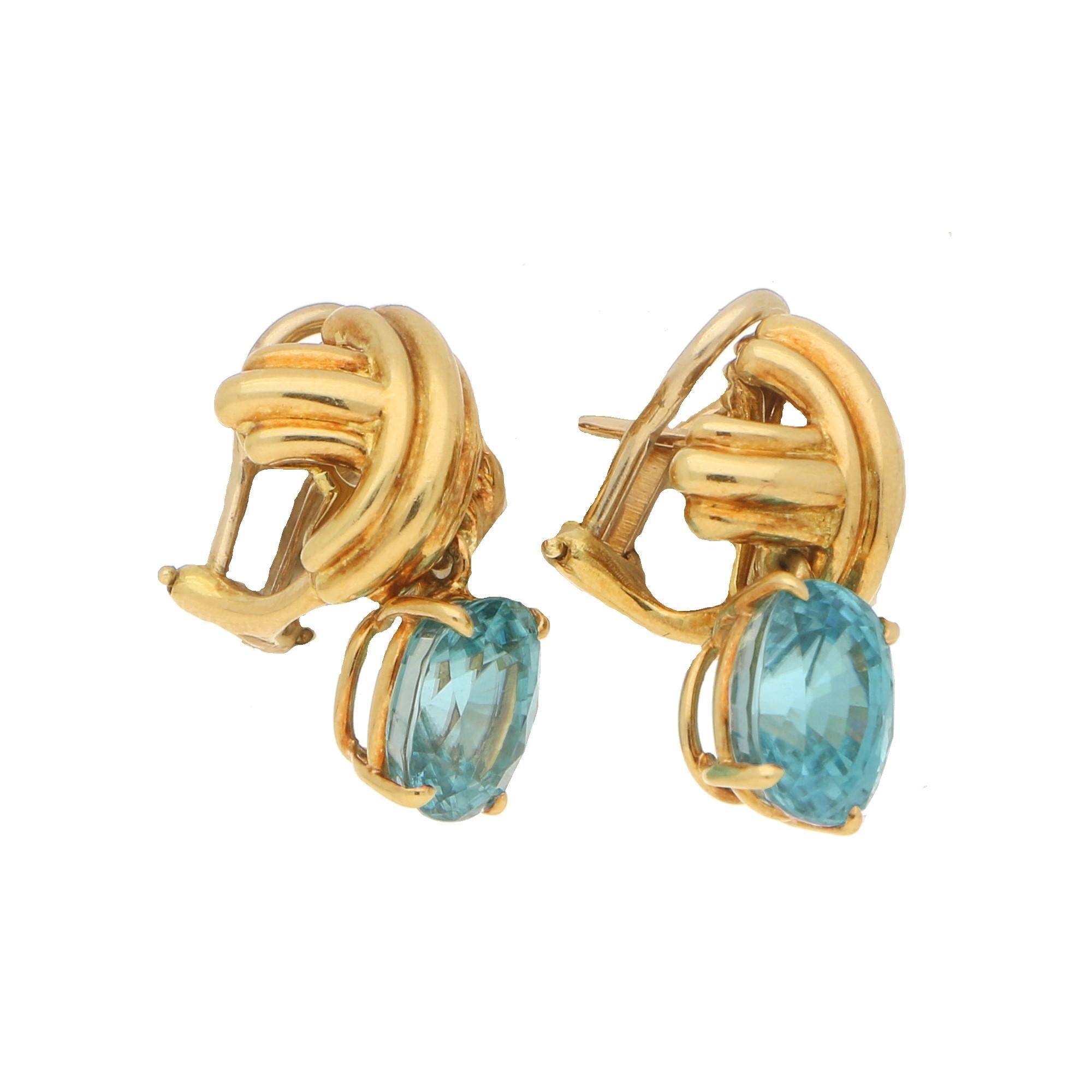 Estimated Zircon weight: 8.00 carats.
An interesting pair of Tiffany & Co. earrings set in 18 carat yellow gold. 
The tops of the earrings feature a cross from which is suspended a strikingly coloured oval cut blue Zircon - a stone popularly used in