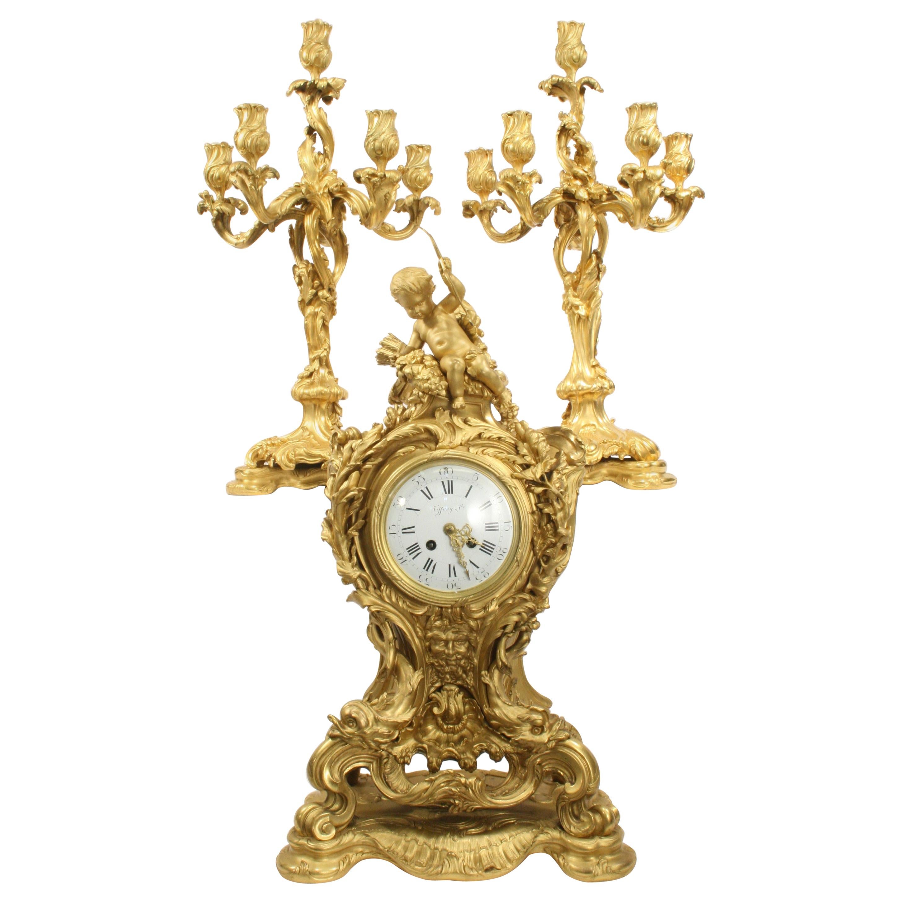 This impressive example of an early 20th century French Rococo palace size clock set comes from the prestigious E. Colin & Cie of Paris foundry. The sculpted ensemble is detailed with crisp elaborate scrolling accented with a full figure cupid with