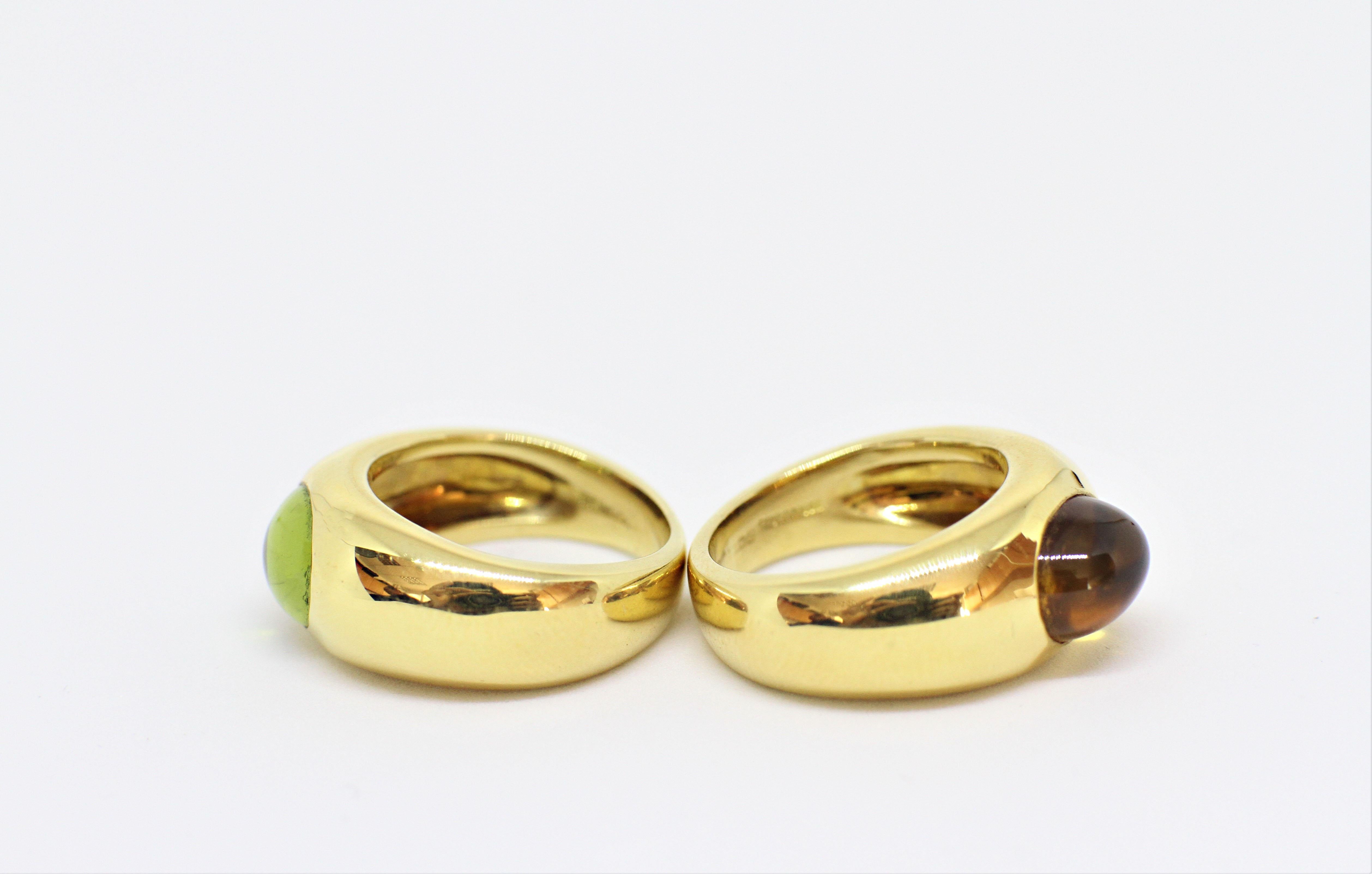 Tiffany & Co set of two 18 carat yellow gold rings. The first ring is set with an oval cabochon citrine in an open back, rub-over setting with an approximate weight of 2.00 carats. The second ring is set with an oval cabochon peridot, also in an