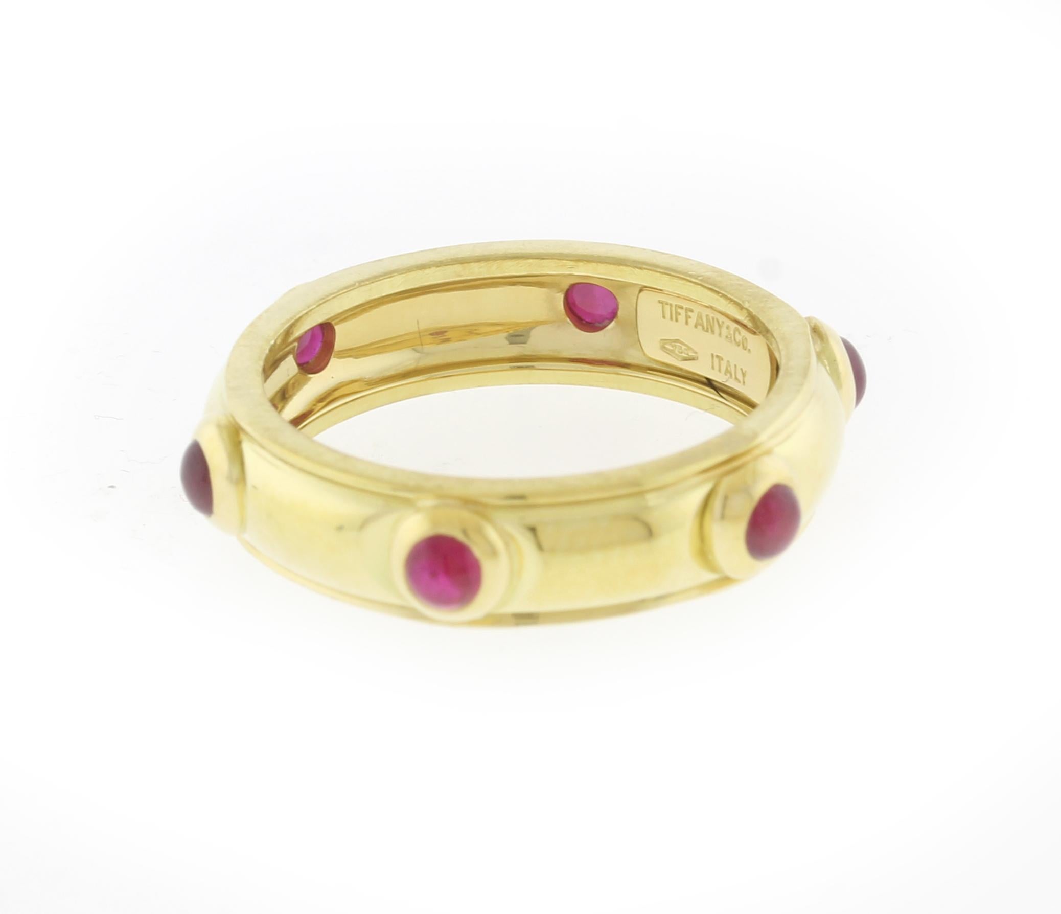 From Tiffany & Co a cabochon ruby band ring. The ring  boast 6 bright 3mm rubies
♦ Designer: Tiffany & Co.
♦ Metal: 18 karat
♦ Circa 1990s
♦ 5.2mm wide
♦ Size 7 ½
♦ 6.3 grams
♦ Packaging: Tiffany Pouch
♦ Condition: Excellent , pre-owned
