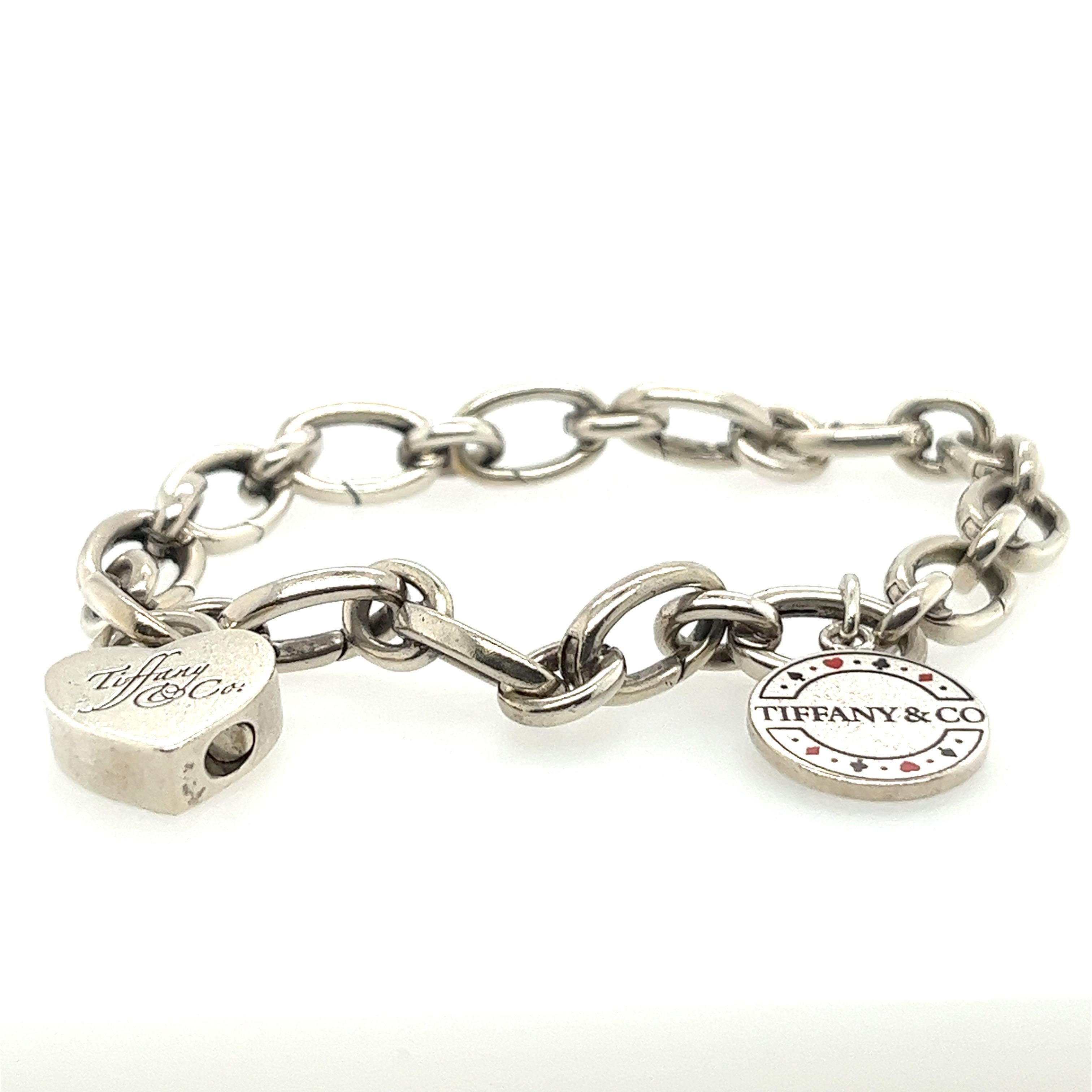 Tiffany & Co charm bracelet with 2 charms. Rare Las Vegas sterling silver & enamel poker chip charm was released as a limited edition. Second charm is a sterling silver heart shaped lock with Tiffany & Co written in cursive.