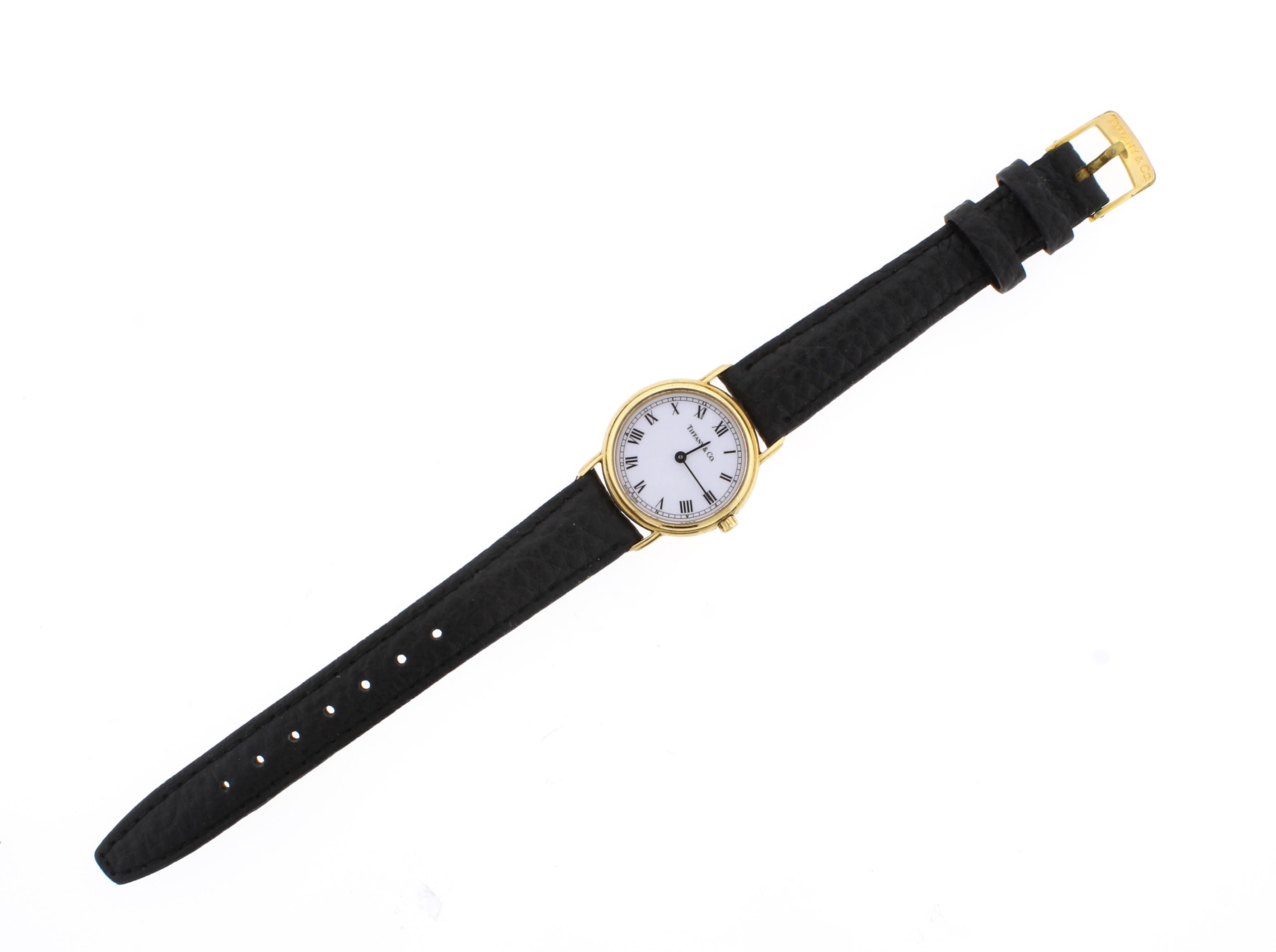 From Tiffany & Co. a ladies wrist watch
♦ Designer: Tiffany & Co.
♦ Metal: 18 karat
♦ Dial: round, white, black Roman numeral hour markers, black outer minute track, black baton hands
♦ Case:  28mm round, snap back, inside: L253,    
♦ Circa 1995
♦