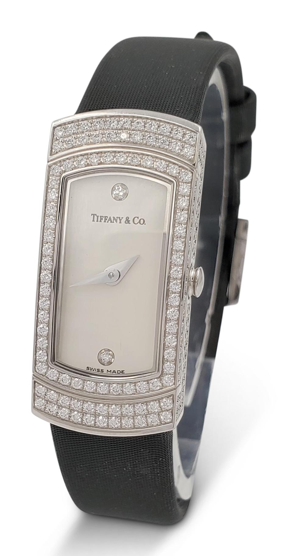 Authentic Tiffany & Co. 'Classique' ladies watch features an elongated rectangular case (13 mm x 29 mm) that is set with an estimated 2.65 carats of high quality round brilliant cut diamonds. The cream dial is accented by one diamond at numerals 12