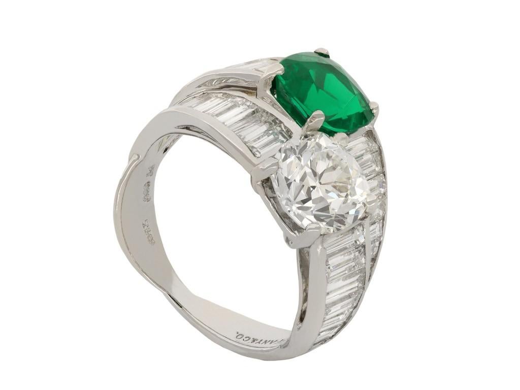 Tiffany & Co. Colombian emerald and diamond crossover ring. Diagonally set with one cushion shape old cut natural Colombian emerald with minor oil in an open back claw setting with a weight of 1.93 carats, further set with one cushion shape old mine