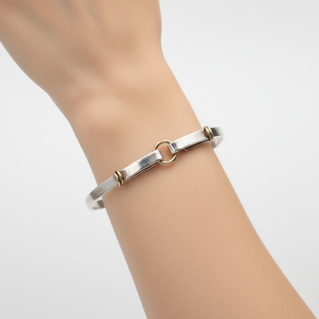 Scopri l'eleganza senza tempo di questo squisito esemplare di Tiffany & Co. Bracciale Combi Hook Bangle, uno splendido esempio della maestria artigianale e del design innovativo del rinomato gioielliere. Questo pezzo sofisticato combina