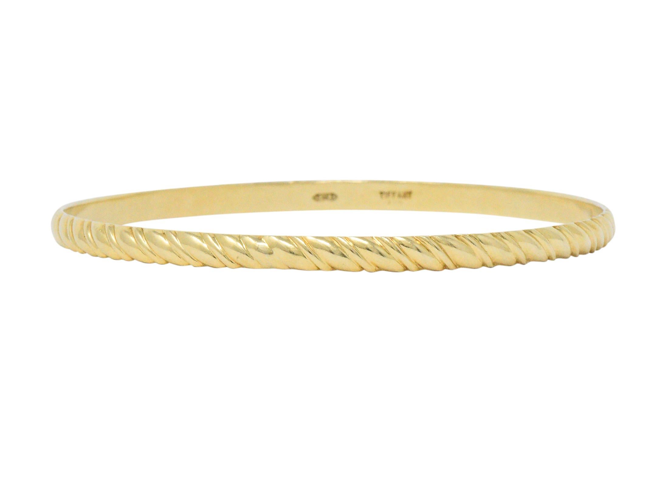 Bangle style bracelet featuring a deeply ribbed texture

Completed by a bright finish

Signed Tiffany

Tested as 14 karat gold

Circa: 1990s

Inner circumference: 7 1/2 inches

Width: 1/8 of an inch

Total weight: 11.5 grams

Thrilling. Stylish.