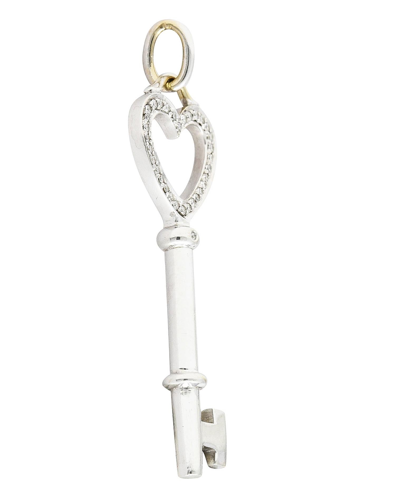 Designed as a skeleton key with heart shaped handle. Accented by round brilliant cut diamonds. Weighing approximately 0.15 carat total. Eye clean and bright - bead set. Completed by jump ring bale. Stamped 750 for 18 karat gold. Fully signed Tiffany