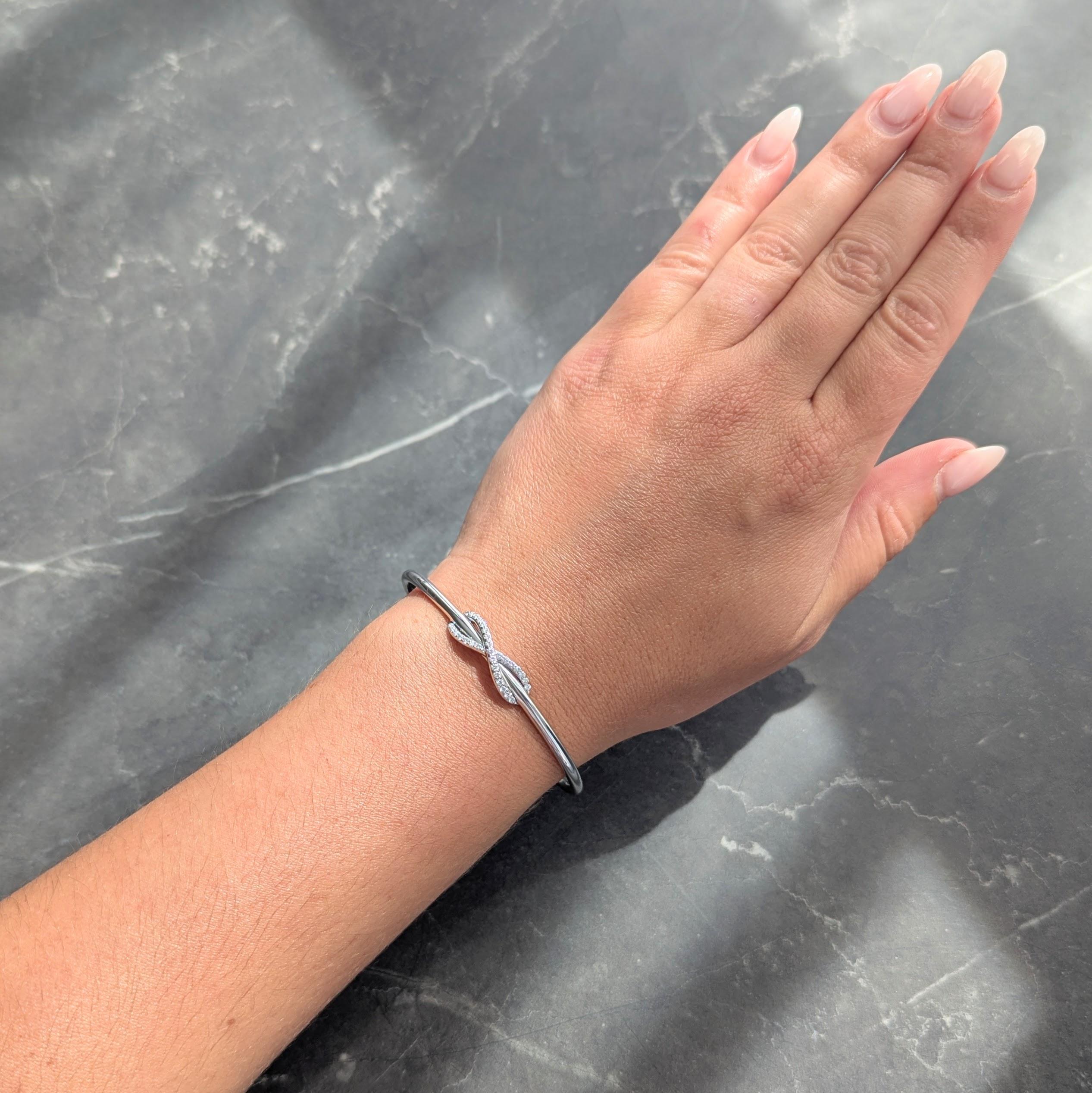 Offenes Armband mit gewebtem Unendlichkeitssymbol in der Mitte
Mit runden Diamanten im Brillantschliff auf der Unendlichkeit und an den Enden gefasst
Rund im Brillantschliff mit einem Gesamtgewicht von etwa 0.39 Karat
Farbe G mit Reinheit VS2 - mit