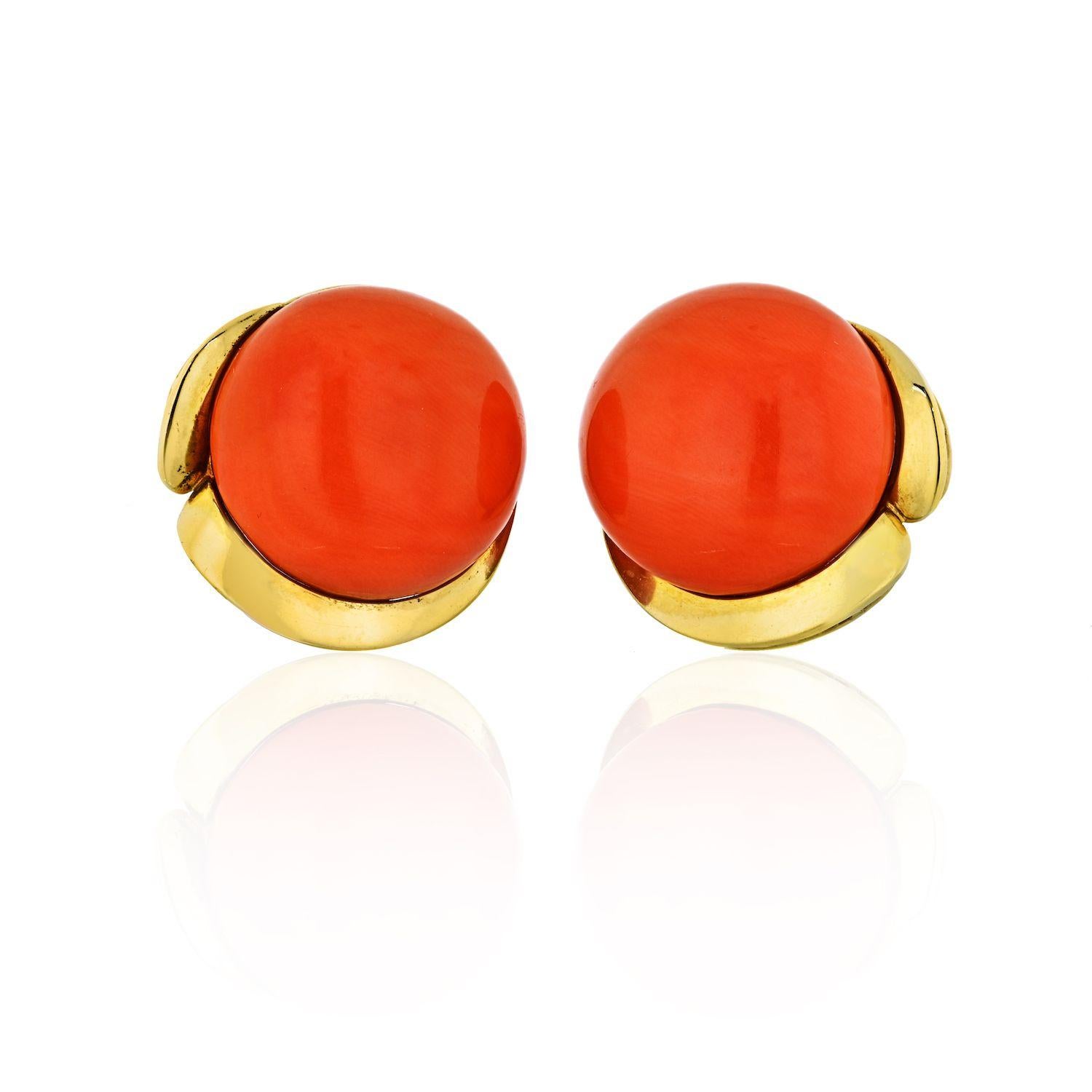 These stunning Tiffany & Co large round earrings are crafted in 18k yellow gold and feature beautiful even color cabochon orange corals measuring 22.6mm, entire earring measures 25.6mm.
Coral is of a vibrant orange color. 
These lever-back clip-on