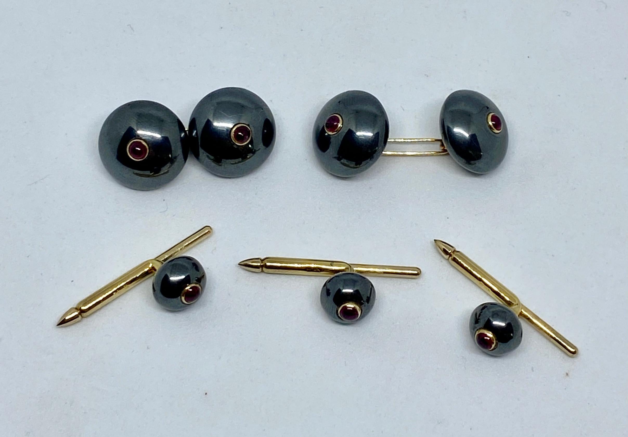 A superb and extremely rare set of double-sided cufflinks and three matching shirt studs made from round hematites with cabochon-cut rubies set in yellow gold. 

The four round cufflinks faces each measure 13.2mm in diameter. The studs measure 7.8mm