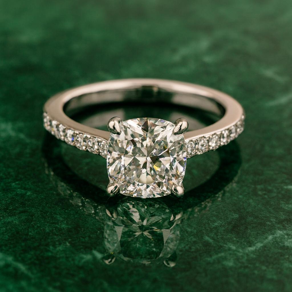 Questo elegante anello di fidanzamento di Tiffany & Co. mette in mostra uno splendido diamante brillante a cuscino da 1,30 carati, che si distingue per l'eccezionale colore F e la purezza VVS1, come certificato da GIA. La pietra centrale presenta