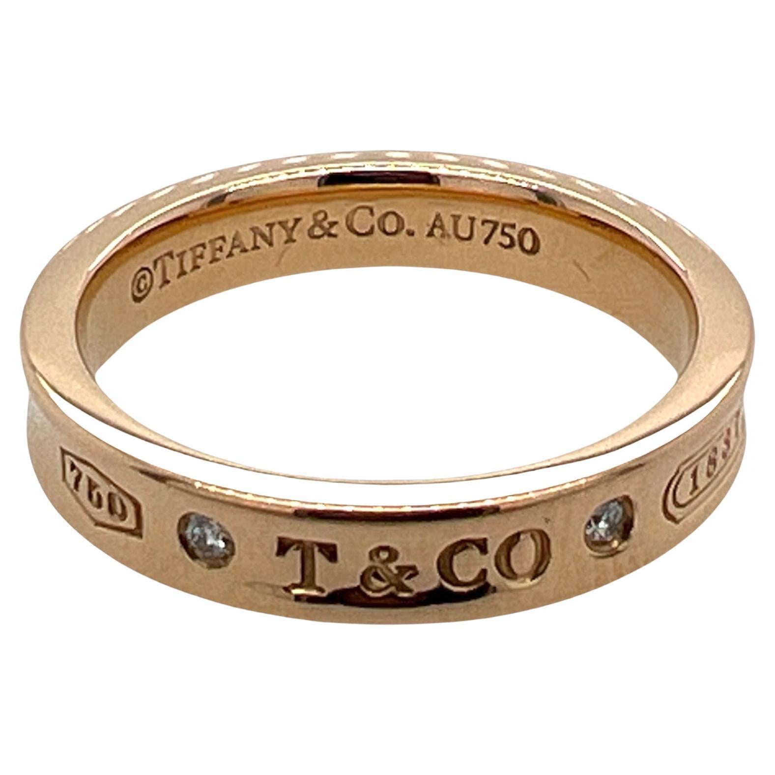 Tiffany & Co. Diamond 1837 band ring fashioned in 18 karat rose gold. The band features 2 round brilliant cut diamonds weighing .03 carat total weight. The band measures 1.5mm in width and is size 7. 