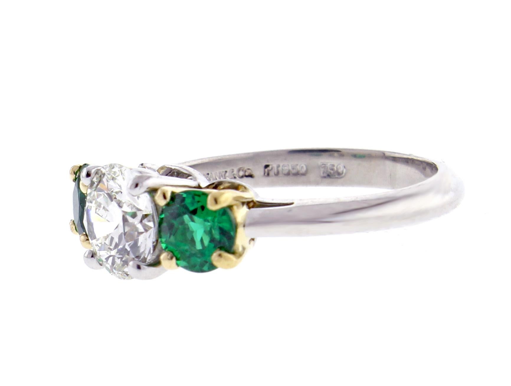 From Tiffany & Co. a Diamond and Emerald Three-stone Ring. The center diamond weighs 1.11 carat, I color and VS1 clarity. The ring is hand made in platinum and 18 karat gold. The two emerald are exceedingly fine and have been fully re-polished.

♦