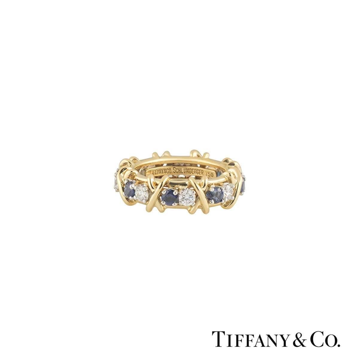 A beautiful 18k yellow gold diamond and sapphire Tiffany & Co. ring from the Schlumberger collection. The ring comprises of 8 round brilliant cut diamonds alternating with 8 round cut sapphires and accentuated with the iconic signature 'X' motif