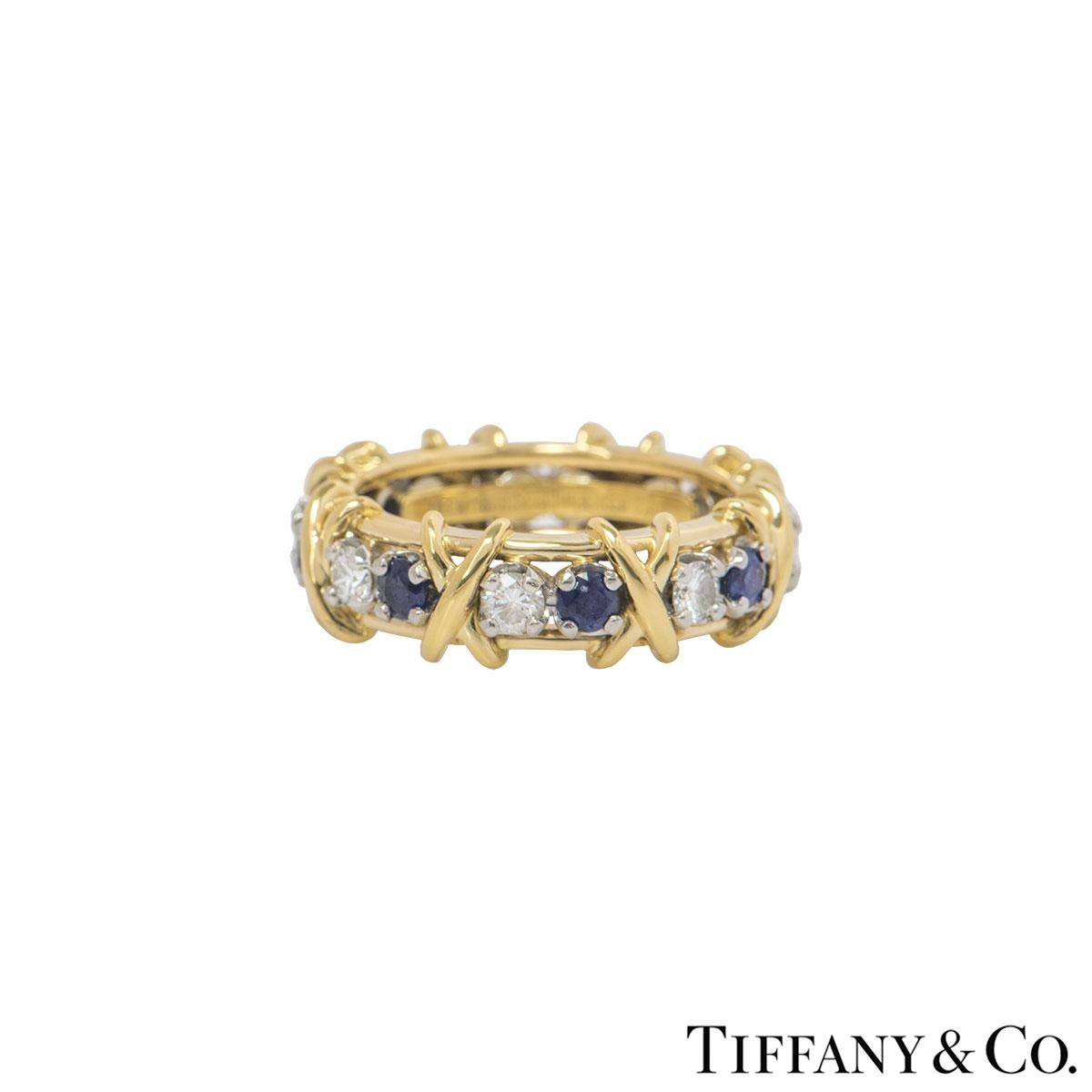 A stunning 18k yellow gold and platinum diamond and sapphire ring by Tiffany & Co. from the Schlumberger collection. The ring features 8 round brilliant cut diamonds alternating with 8 round cut sapphires with the iconic signature 'X' motif between