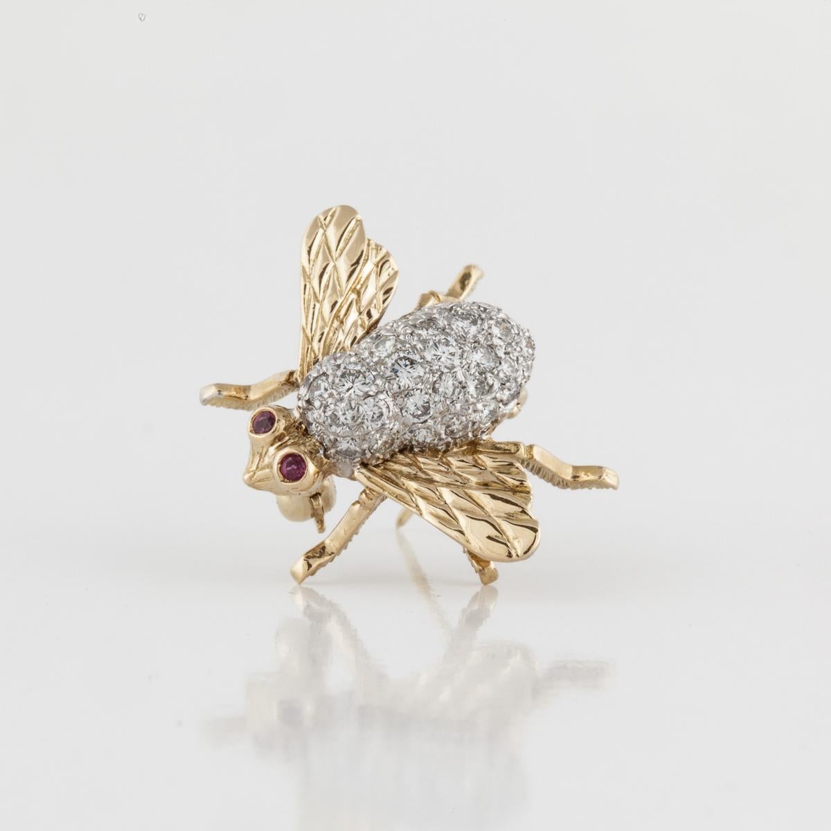 Tiffany & Co. diamond bee pin in 18K yellow and white gold.  Features two round ruby eyes and thirty-seven round diamonds that total 1.30 carats; H-I color and VS1-VS2 clarity.  Pin measures 1 inch by 3/4 of an inch.