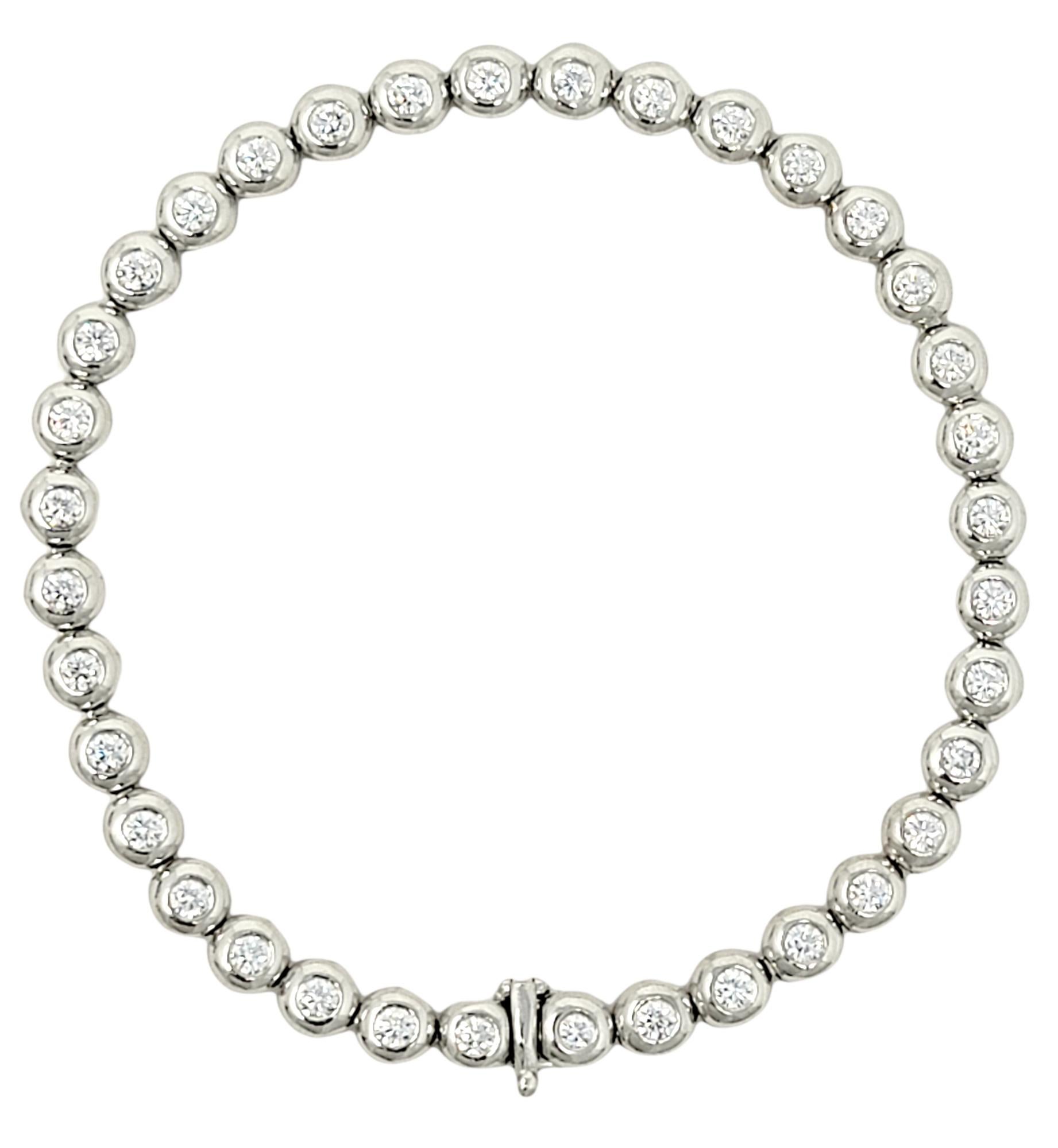 This is an absolutely stunning Tiffany & Co. 'Doughnut' diamond and platinum line bracelet. 36 round, icy white natural diamonds are each bezel set in polished platinum and arranged in a single elegant row. This modern take on the classic tennis