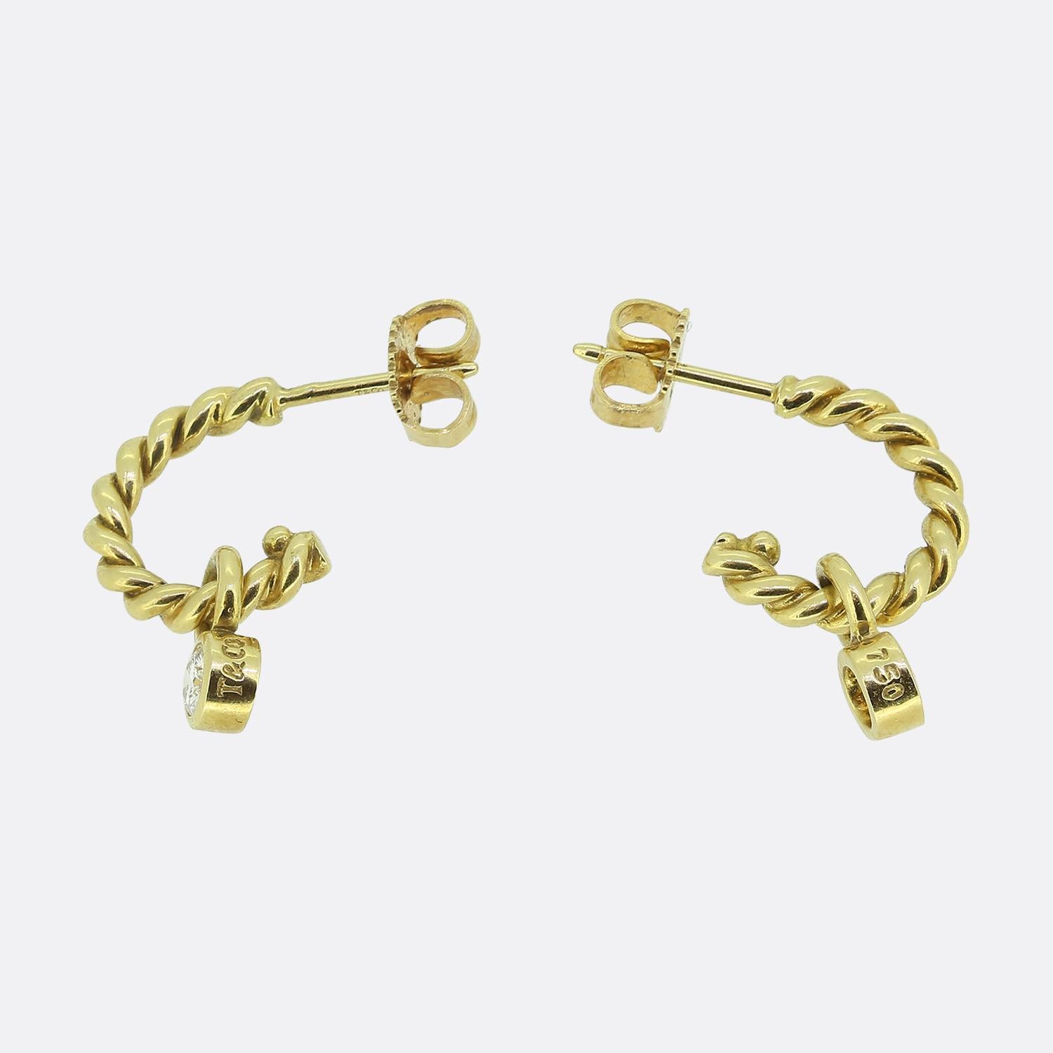 Here we have a lovely pair of rich 18ct yellow gold hoop earrings from the world renowned jewellery designer, Tiffany & Co. Each identical piece features a twisted hoop design, which plays host a single dangling round brilliant-cut diamond below in