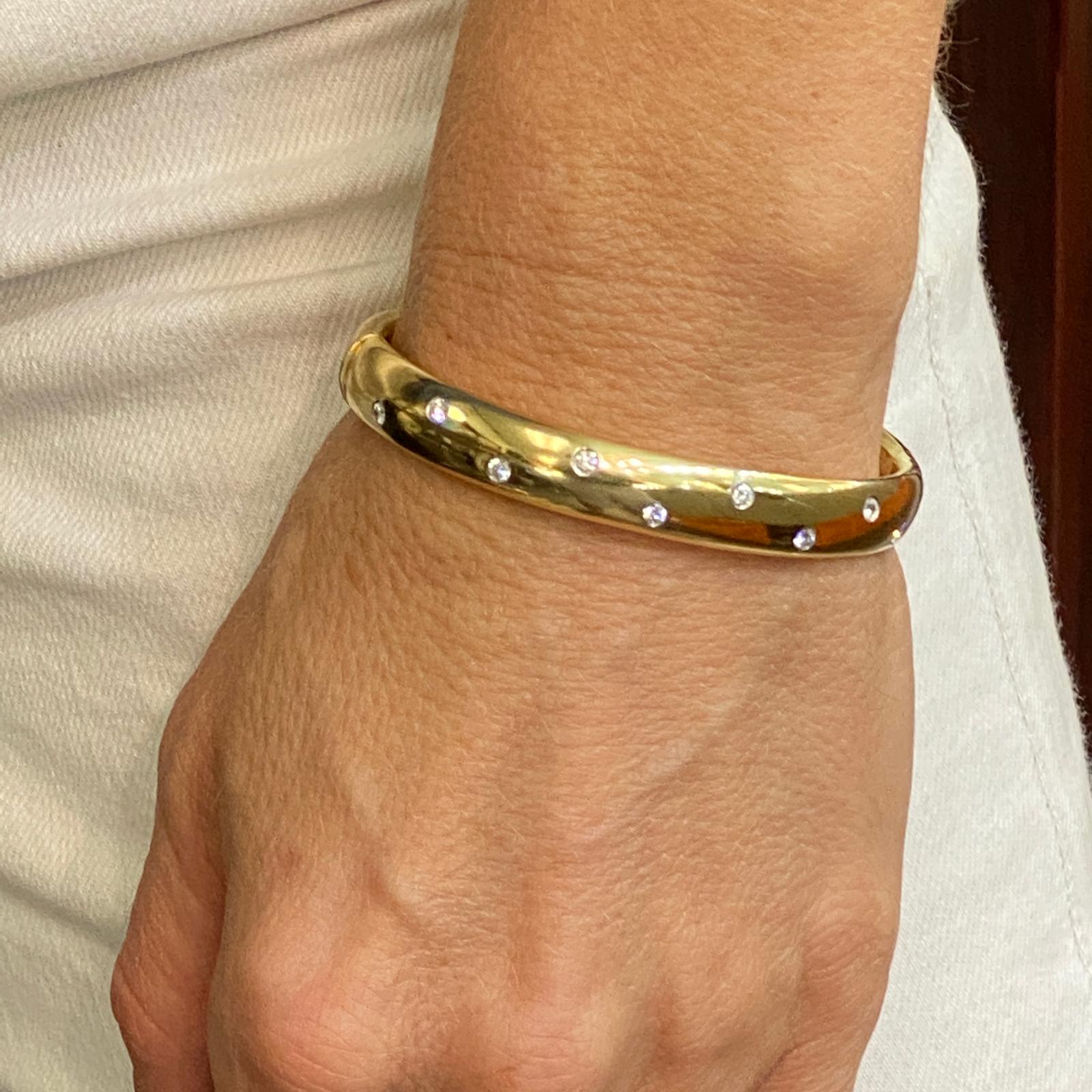 Simple and modern, the wide Etoile bangle is fashioned in 18 karat yellow gold.  The  bangle is punctuated with 10 round brilliant diamonds weighing approximately .50 carat total weight graded F-G/VS.  This elegant bangle is a timeless finishing