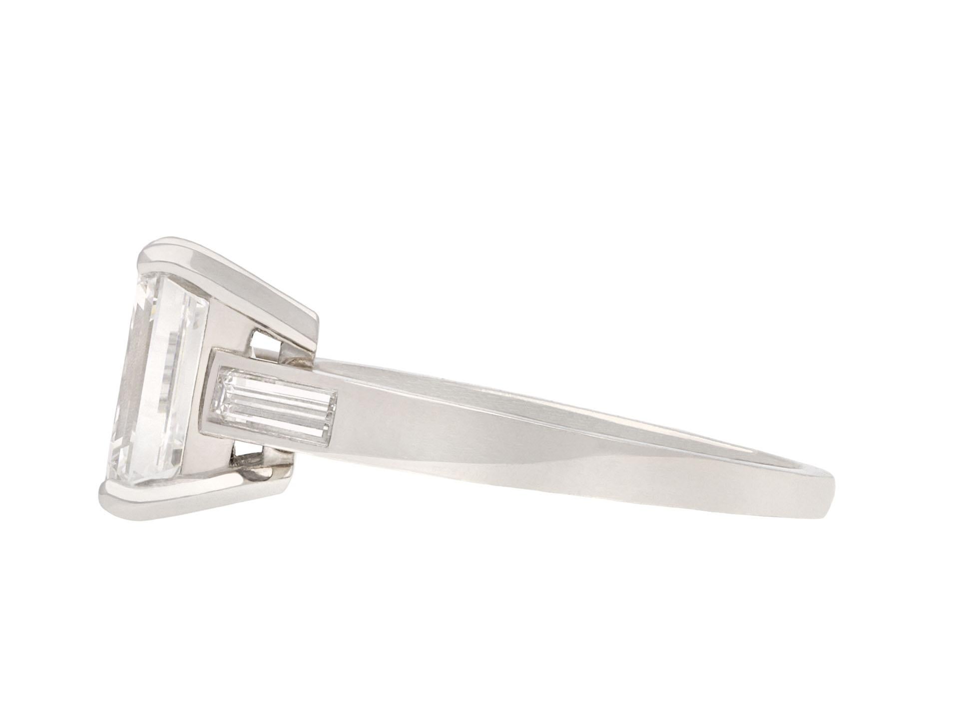 Tiffany & Co. diamond flanked solitaire ring. Set to centre with an emerald-cut diamond, E colour, VVS1 clarity, with a weight of 2.01 carats in an open back claw setting, flanked by two rectangular baguette cut diamonds in open back rubover