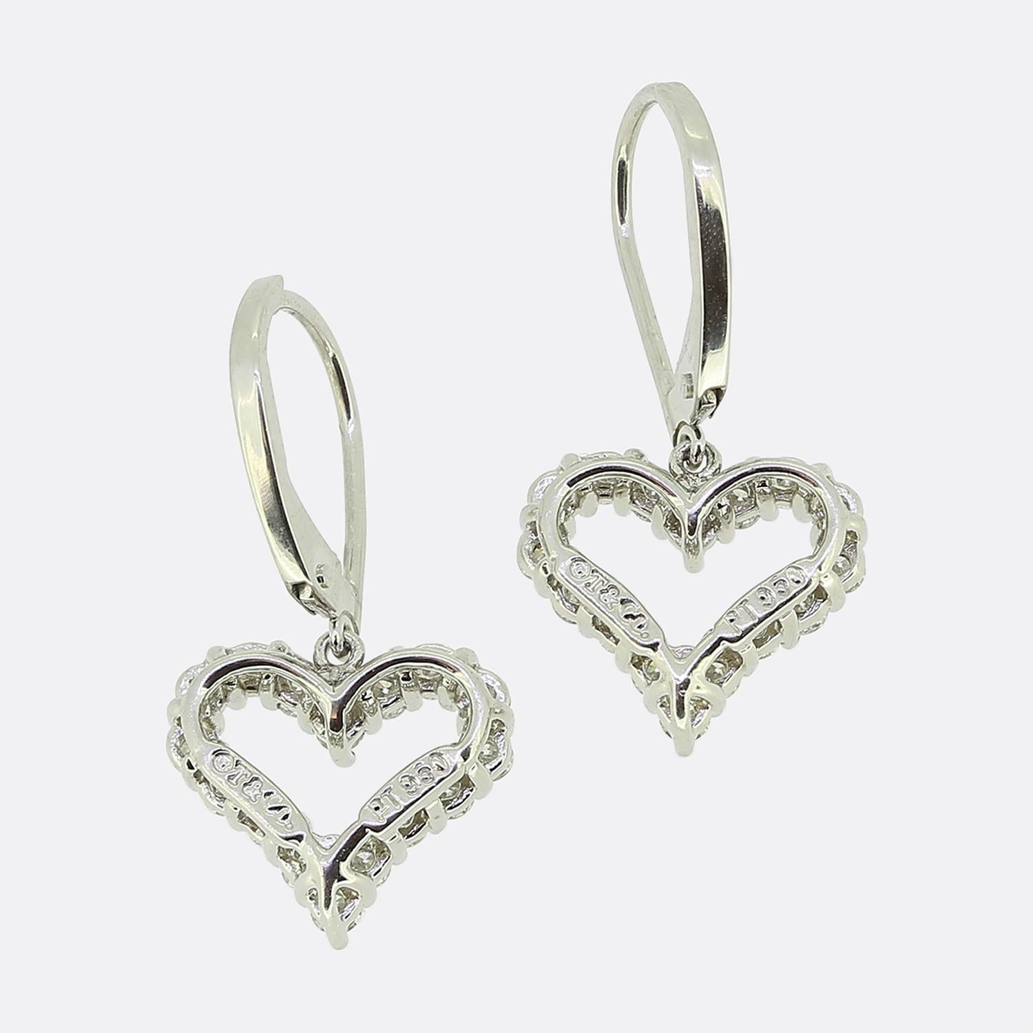 Voici une ravissante paire de boucles d'oreilles pendantes en diamant du créateur de bijoux de renommée mondiale Tiffany & Co. Chaque pièce a été fabriquée en platine en forme de cœur d'amour ouvert, les deux cadres étant sertis d'une seule ligne de