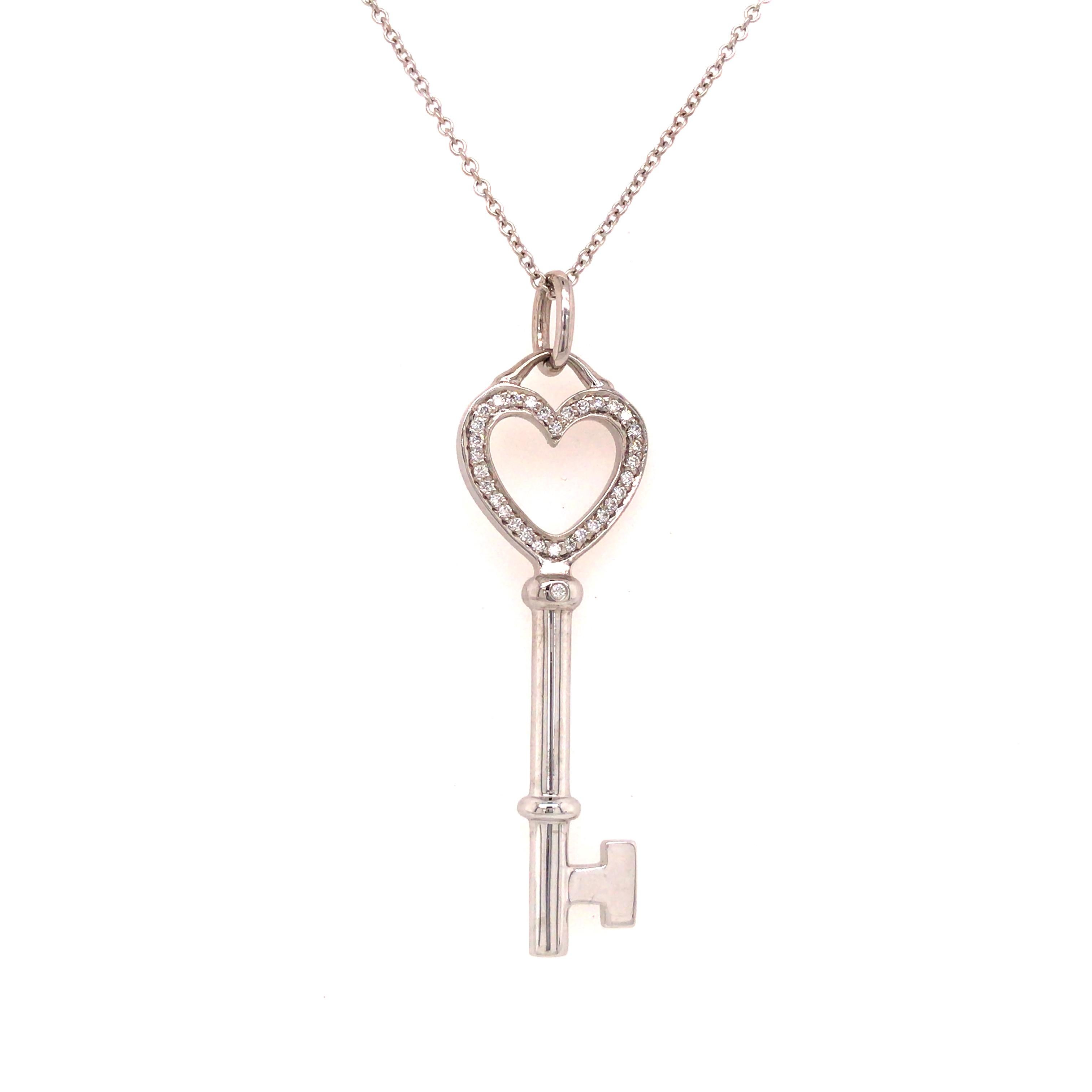 Tiffany & Co. Diamond Heart Key Pendant in 18K White Gold.  Round Brilliant Cut Diamonds weighing 0.08 carat total weight, F-G in color and VS in clarity are expertly set in the heart shape top.  The Pendant measures 1 5/8 inch in length including