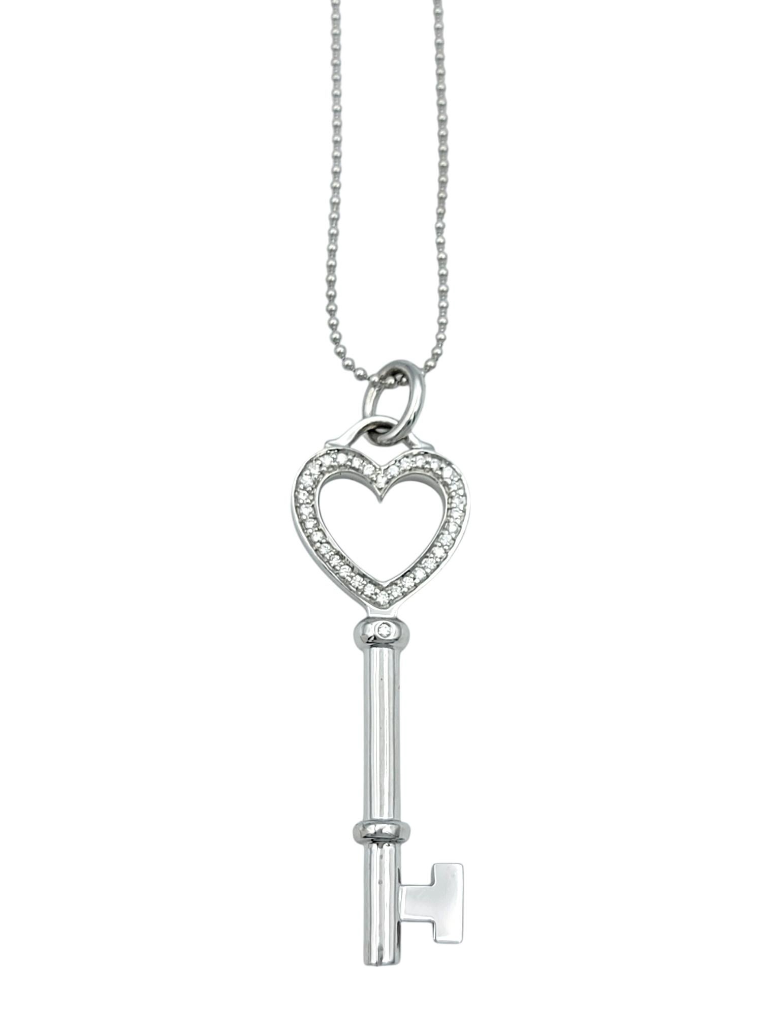 Unlock timeless elegance with this authentic Tiffany & Co. diamond heart key pendant. Crafted in luminous 18 karat white gold, this enchanting design features a delicate heart-shaped top, symbolizing love and sophistication. The pendant is adorned