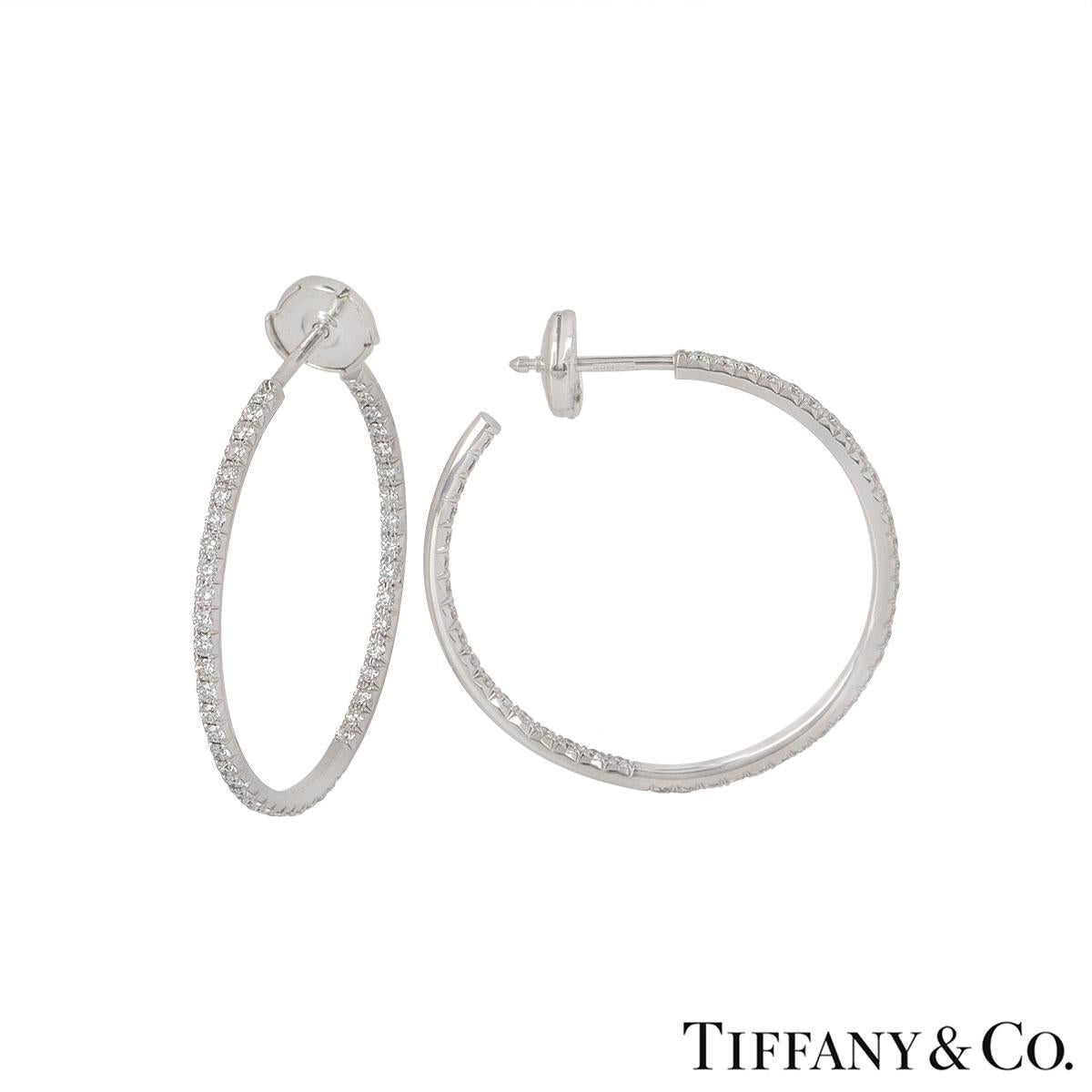 A pair of 18k white gold diamond hoop earrings by Tiffany & Co. The earrings consist of approximately 96 round brilliant cut diamonds set on the outer and inner line of the hoops with an approximate total weight of 0.96ct. The earrings feature post