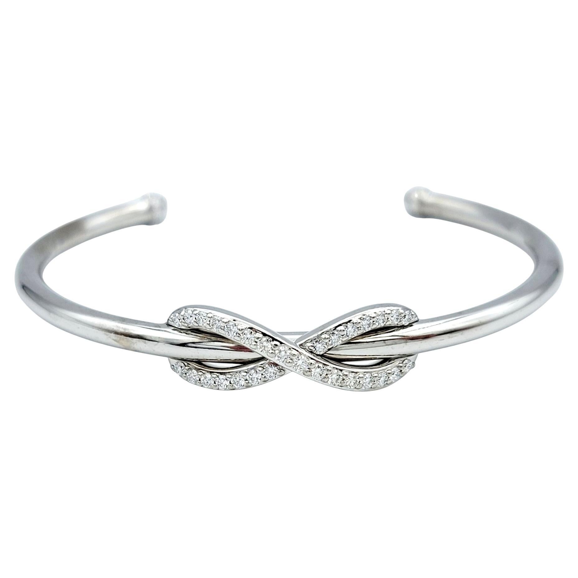 Wrap your wrist in timeless sophistication with the Tiffany & Co. Infinity cuff bracelet, a captivating emblem of elegance. Crafted in radiant 18 karat white gold, this bracelet carries the prestige and allure of Tiffany’s renowned Infinity
