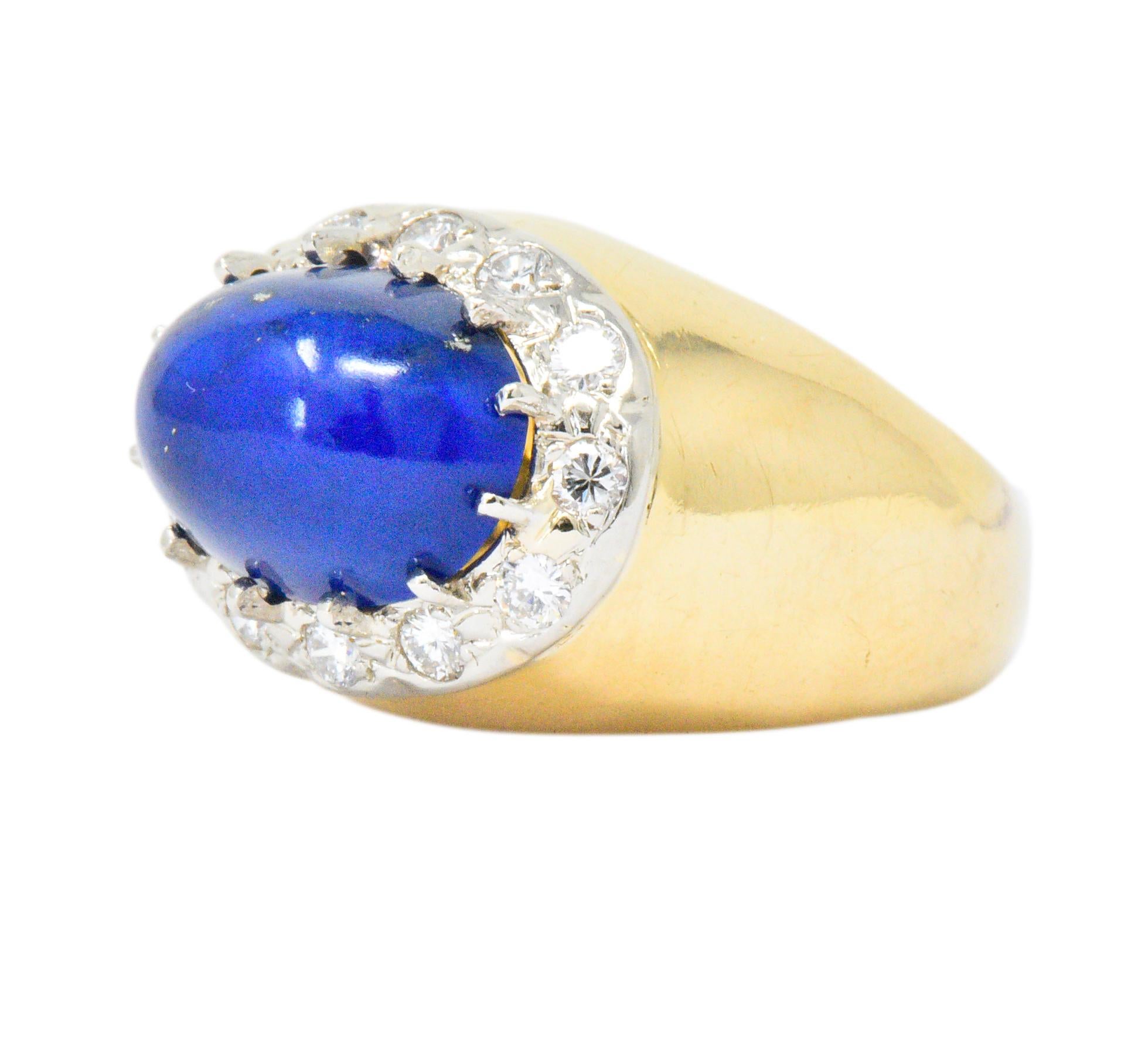 Centering an oval cabochon lapis lazuli measuring approximately 12.6 x  8.8 mm, rich royal blue with flecks of pyrite

With an 18 karat white gold surround containing twelve round brilliant cut diamonds weighing approximately 0.55 carat total, G