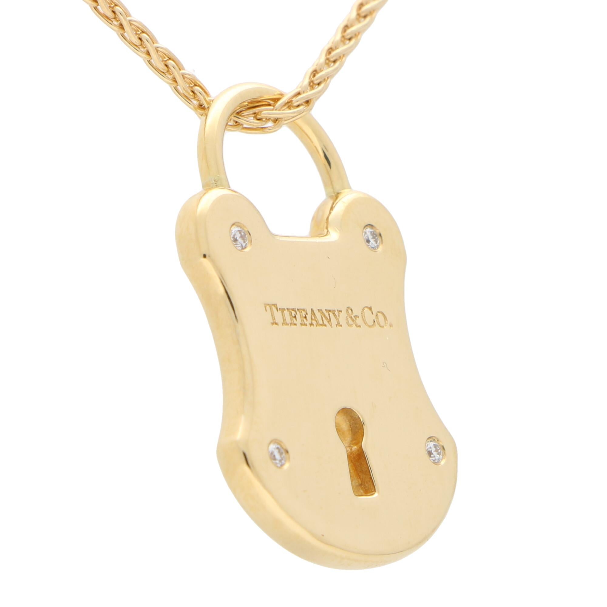 A beautiful signed Tiffany & Co. diamond lock pendant set in solid 18k yellow gold.

The pendant depicts a large lock motif and hangs elegantly from the hatch. To each corner of the pendant are rub-over set round brilliant cut diamonds that depict